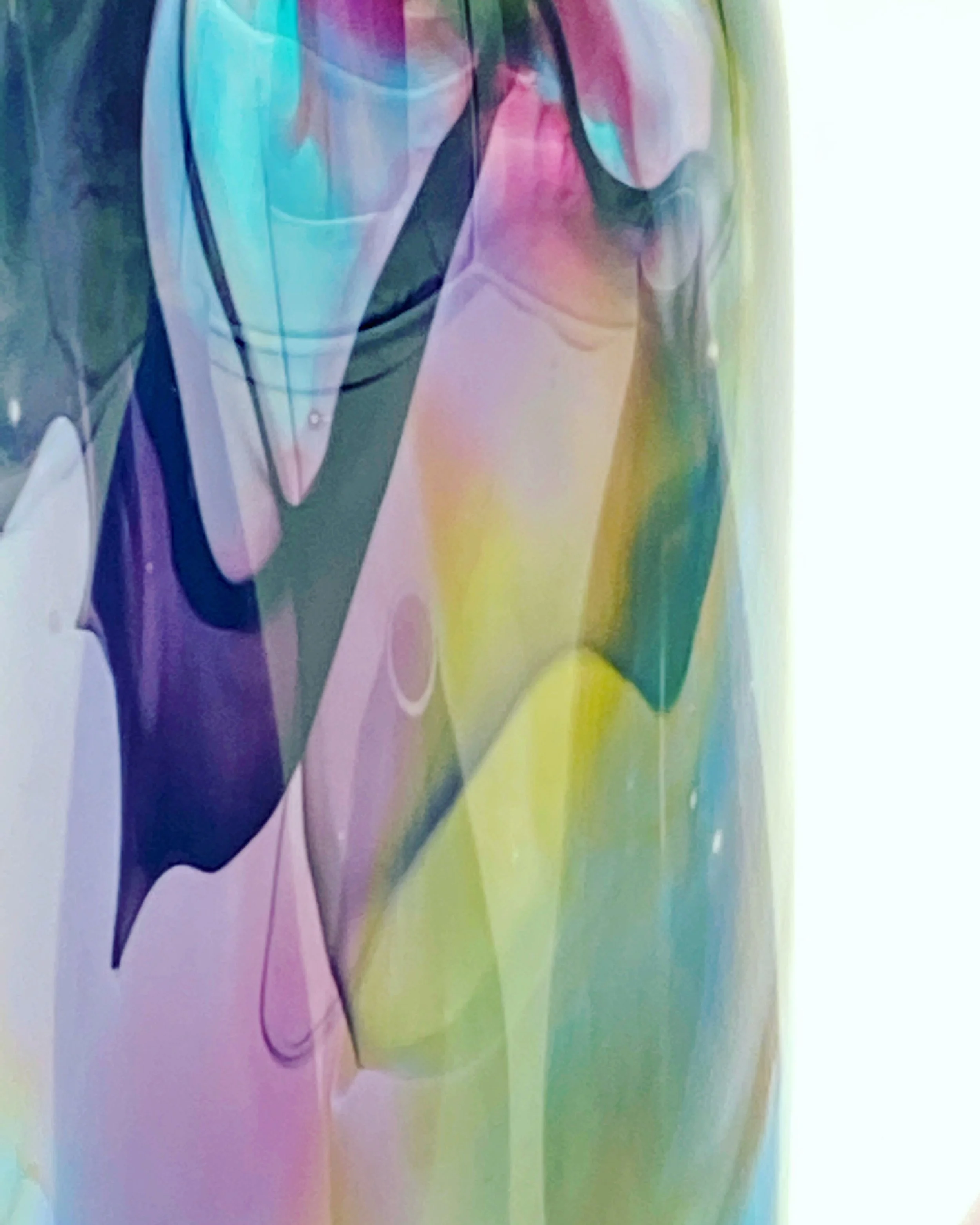 Close-up of an Aurora vase a colorful abstract painterly effect made with blown glass with flowing lines and vibrant hues including pink, purple, yellow, green, and blue.