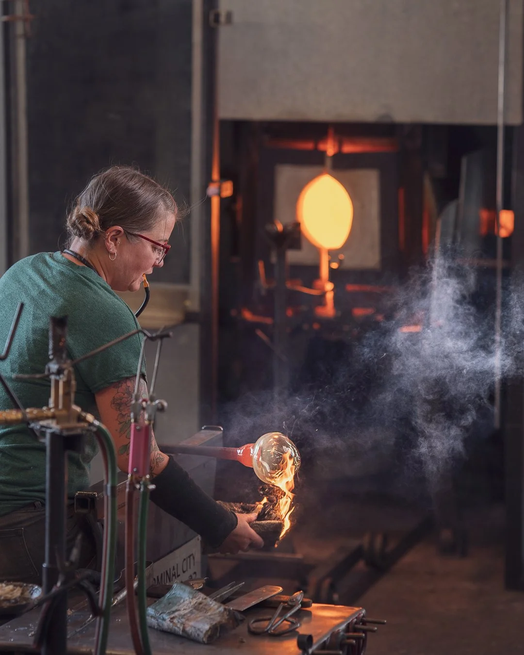 Sonya shaping molten glass with a torch in a glassblowing studio.