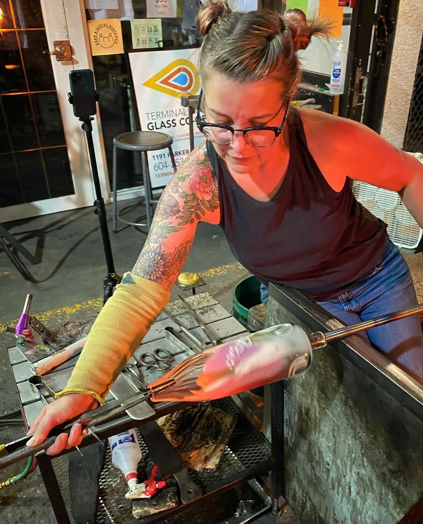 Sonya working on a glassblowing project, shaping molten glass with tools