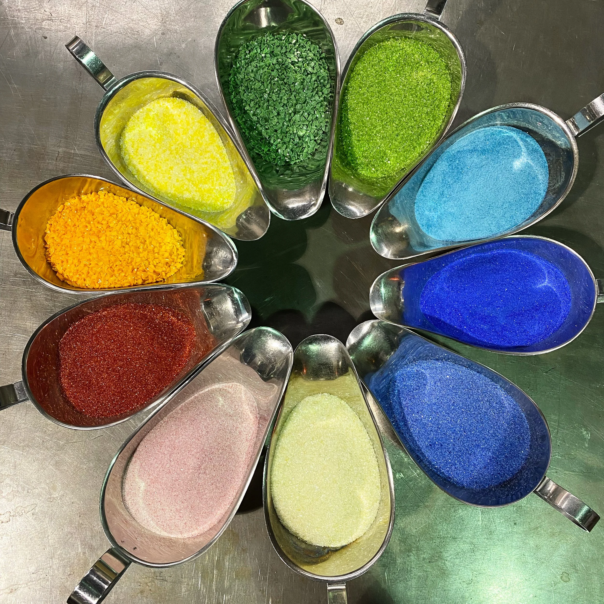 Colorful glass colours in metal cups arranged on a metallic surface.