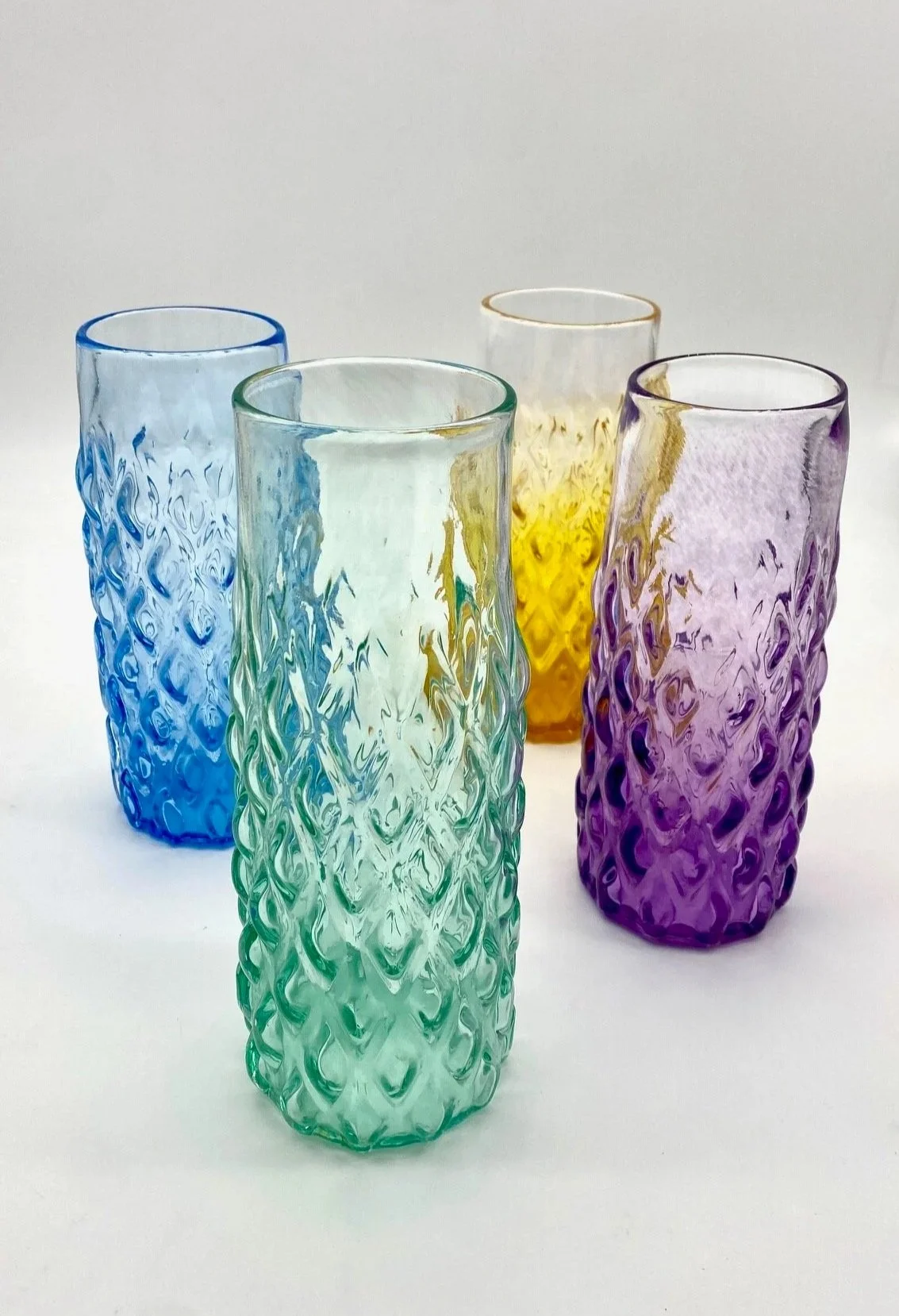 Four tall GEM, textured glass vases in blue, green, yellow, and purple, arranged on a white background.