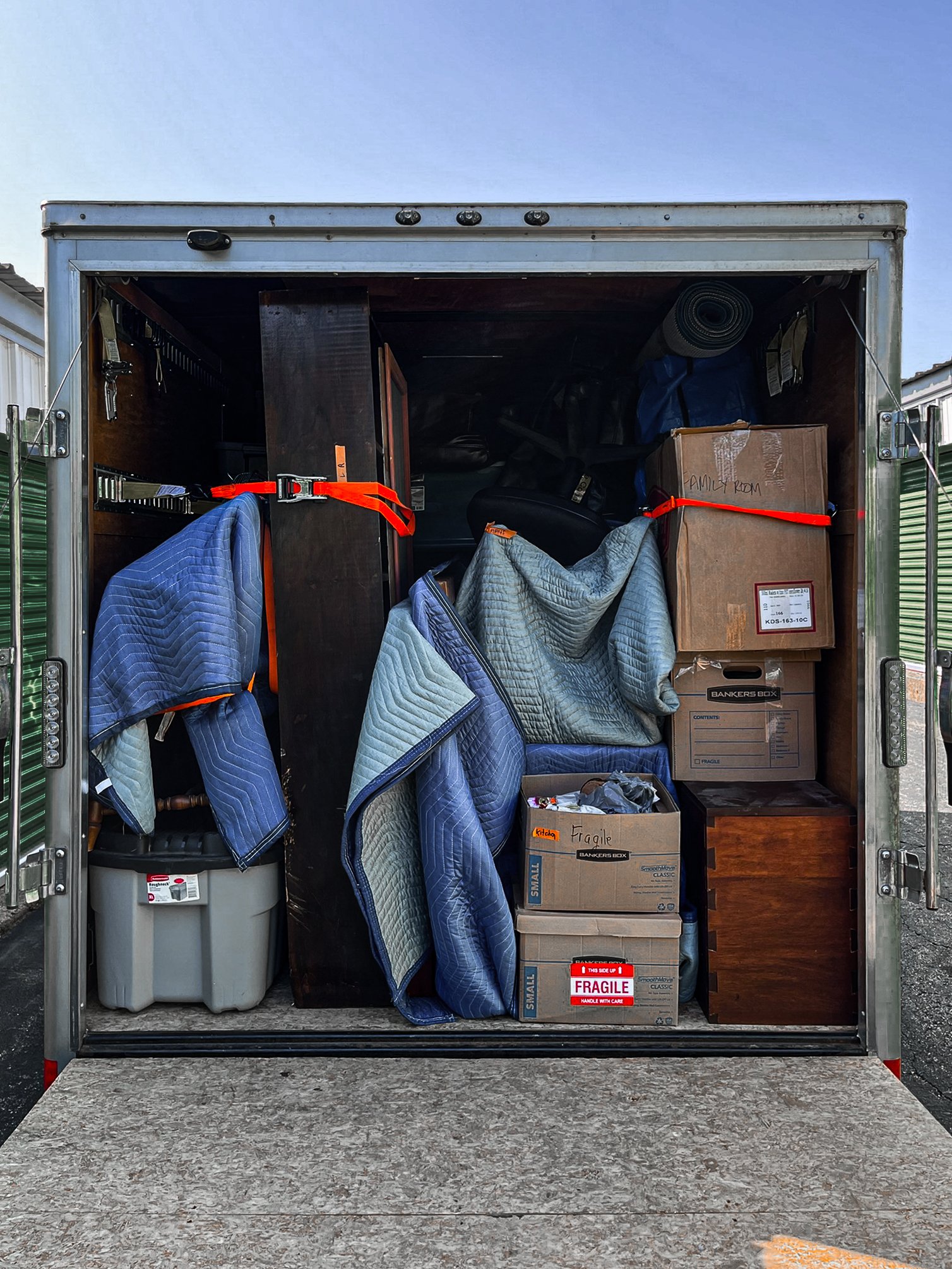 The back of a Splitrock Moving + Logistics's enclosed trailer moving truck packed with boxes, furniture, and blankets.