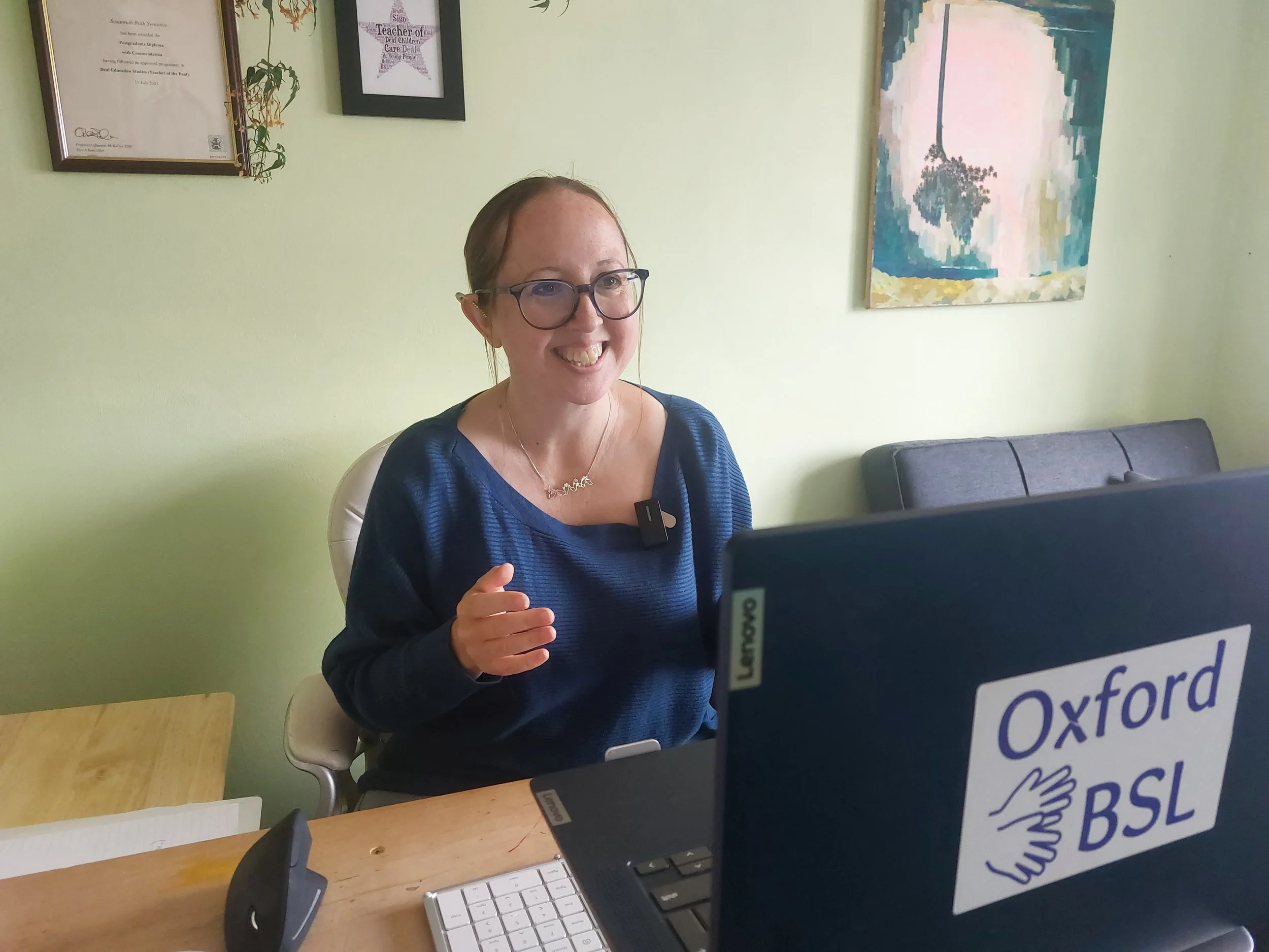 Suzi wearing a blue top, sitting at her laptop and delivering a webinar.