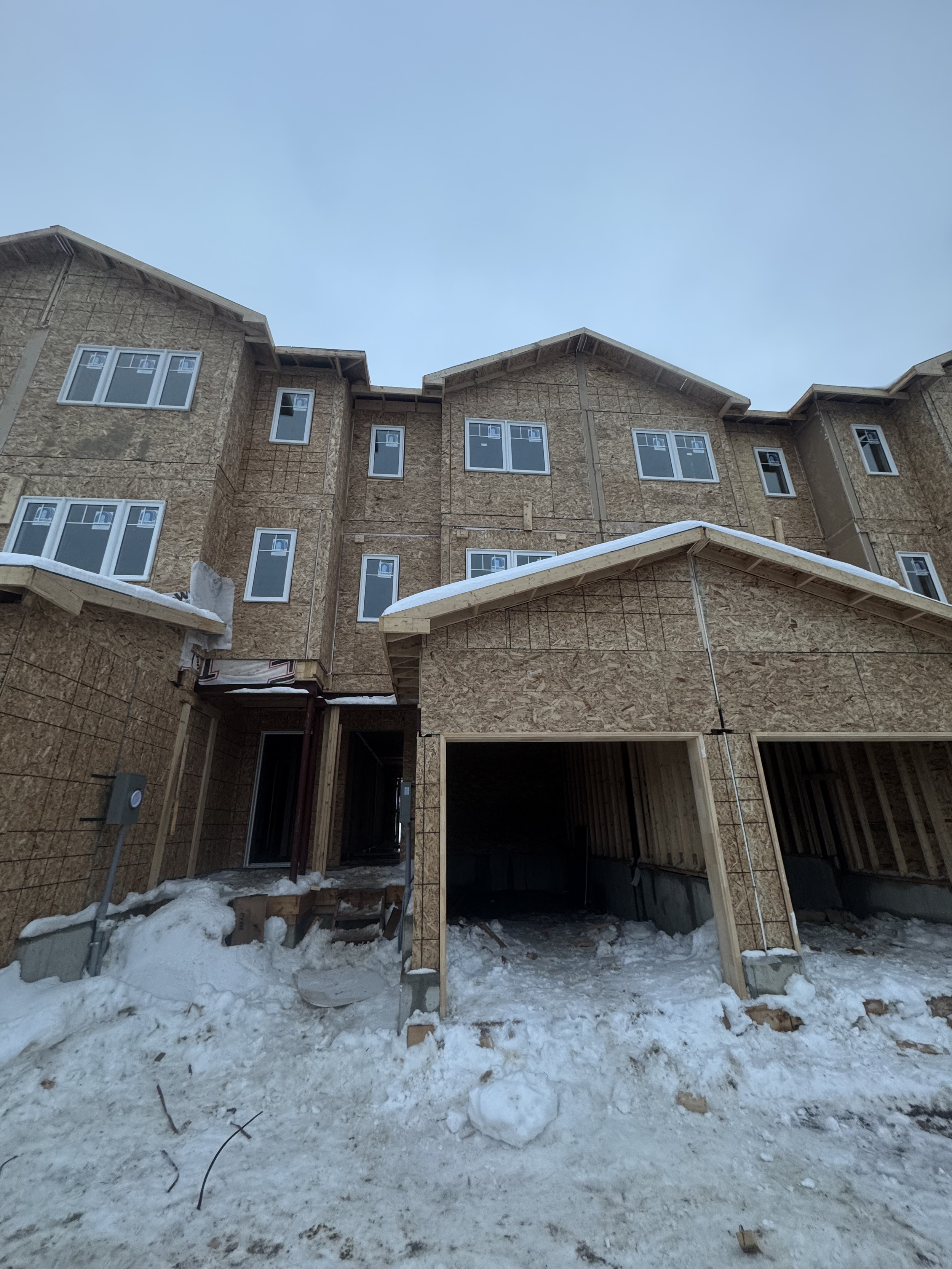 Under construction multi-story residential building with snow on ground in winter.