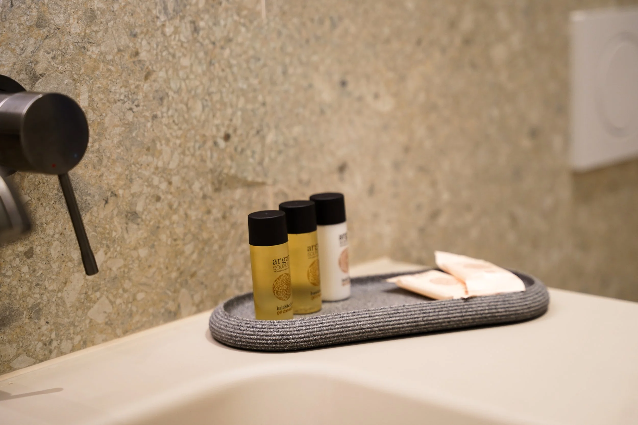 Reise-Set mit kleinen Flaschen, Tablett mit Seife auf einem Waschbecken