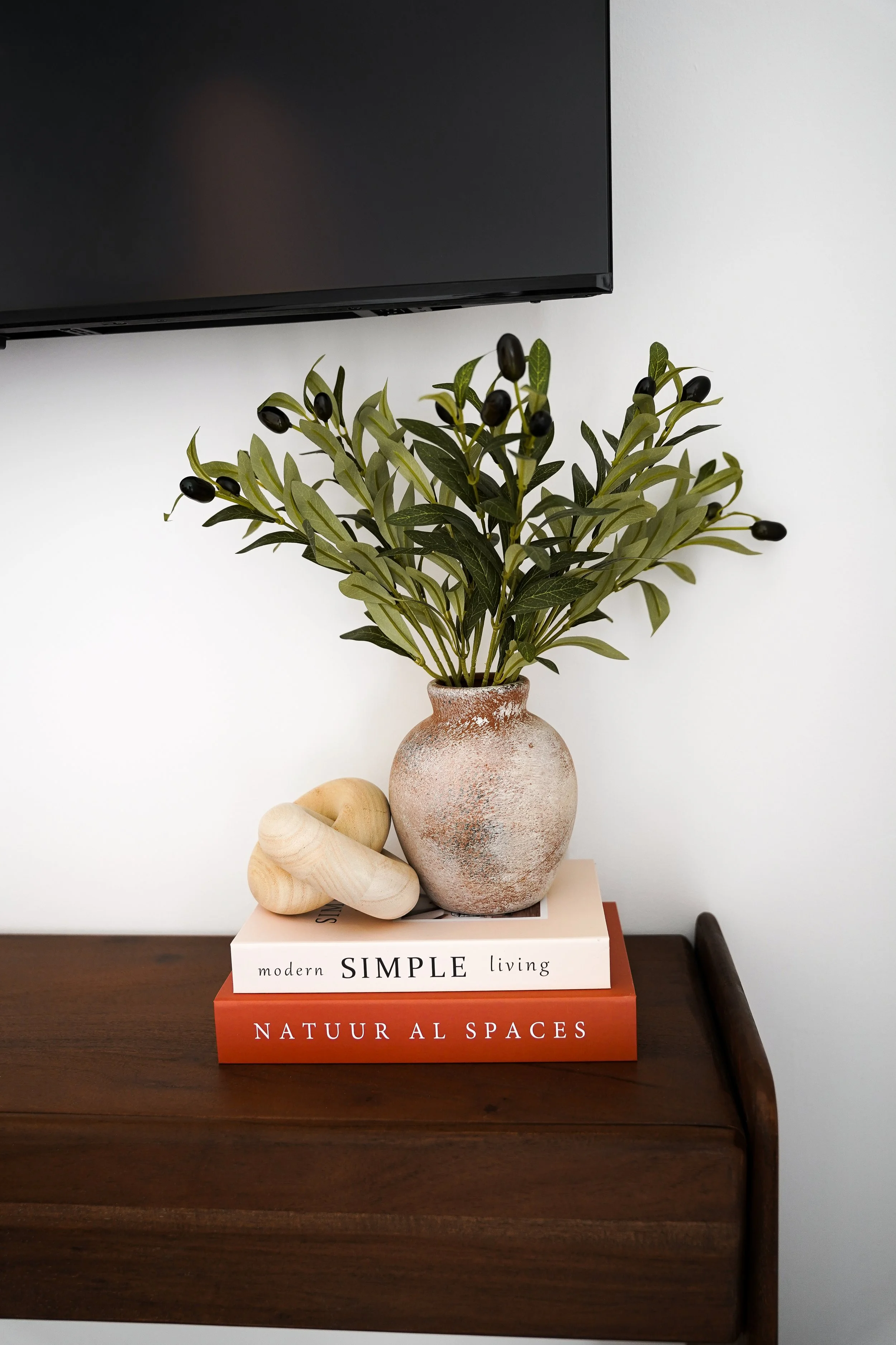 Blumenstrauß in einer Vase auf einem Holztisch, darunter zwei Bücher, eines mit dem Titel 'Modern SIMPLE living' und das andere 'NATUUR AL SPACES'.