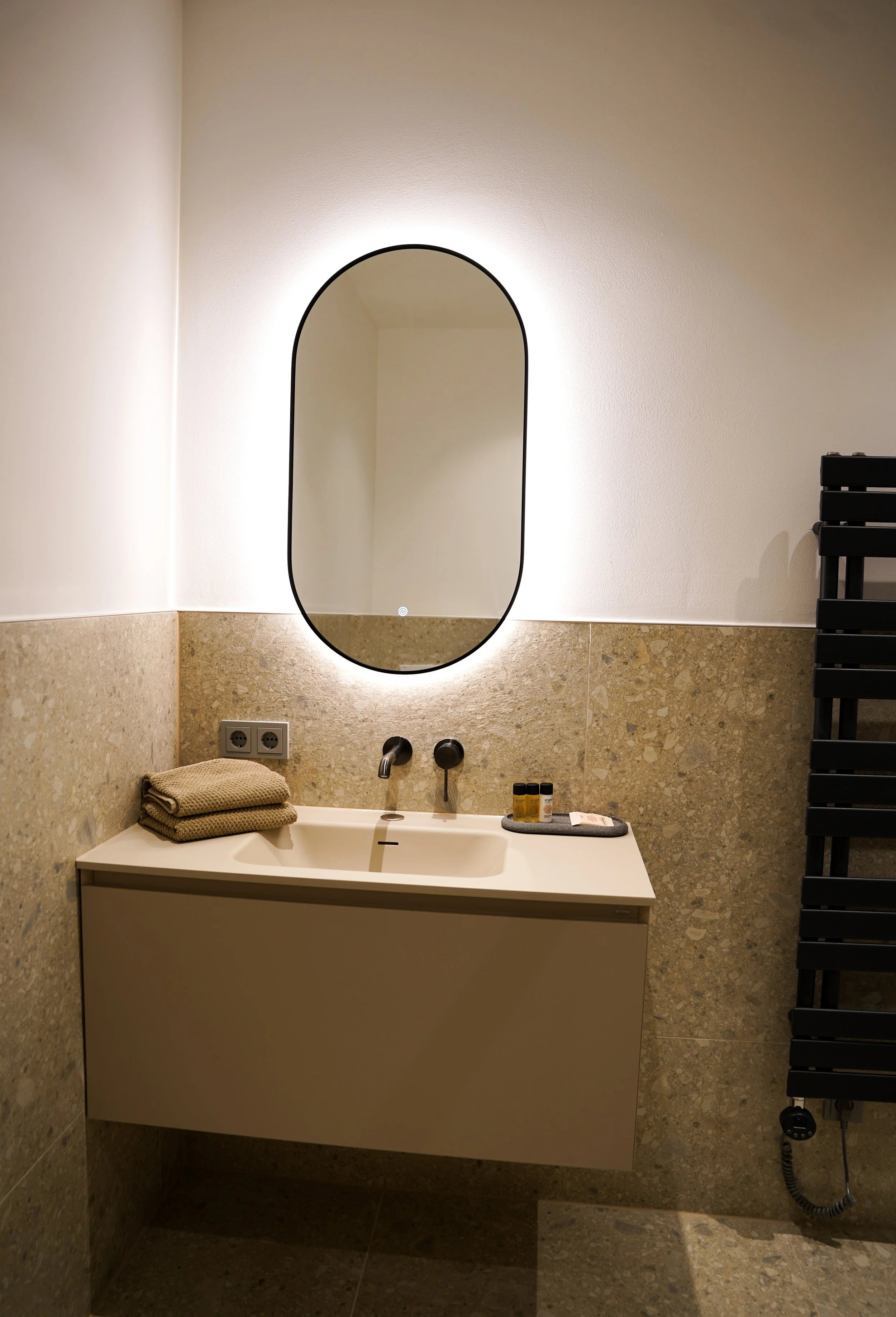 Moderner Waschraum mit Spiegel, Waschtisch und schwarzen Heizkörper, warme Beleuchtung