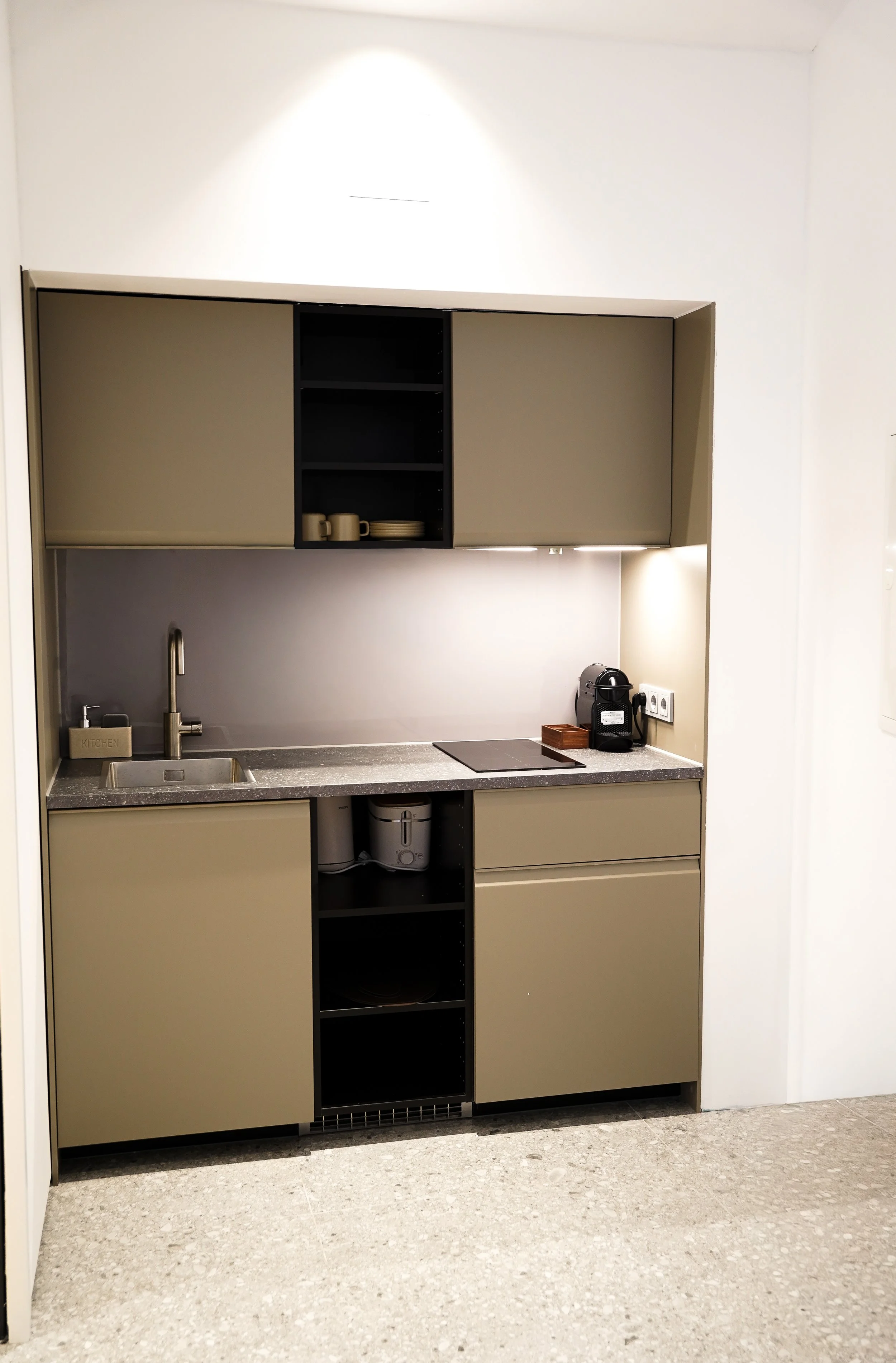 Kleine moderne Küchenzeile mit Spüle, Kaffeeautomat und Geschirr