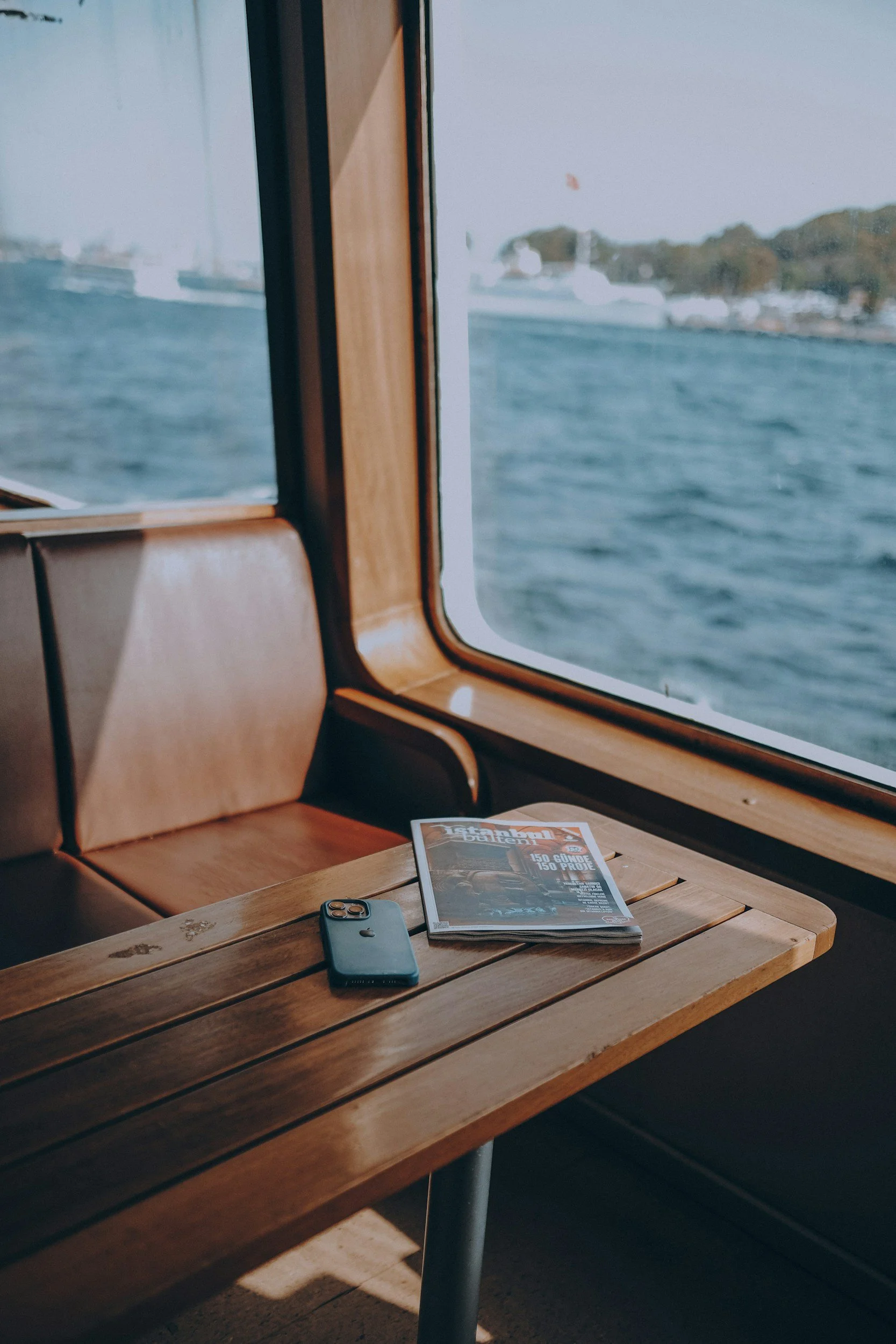 A wooden bench beside a ferry window looking out over the water