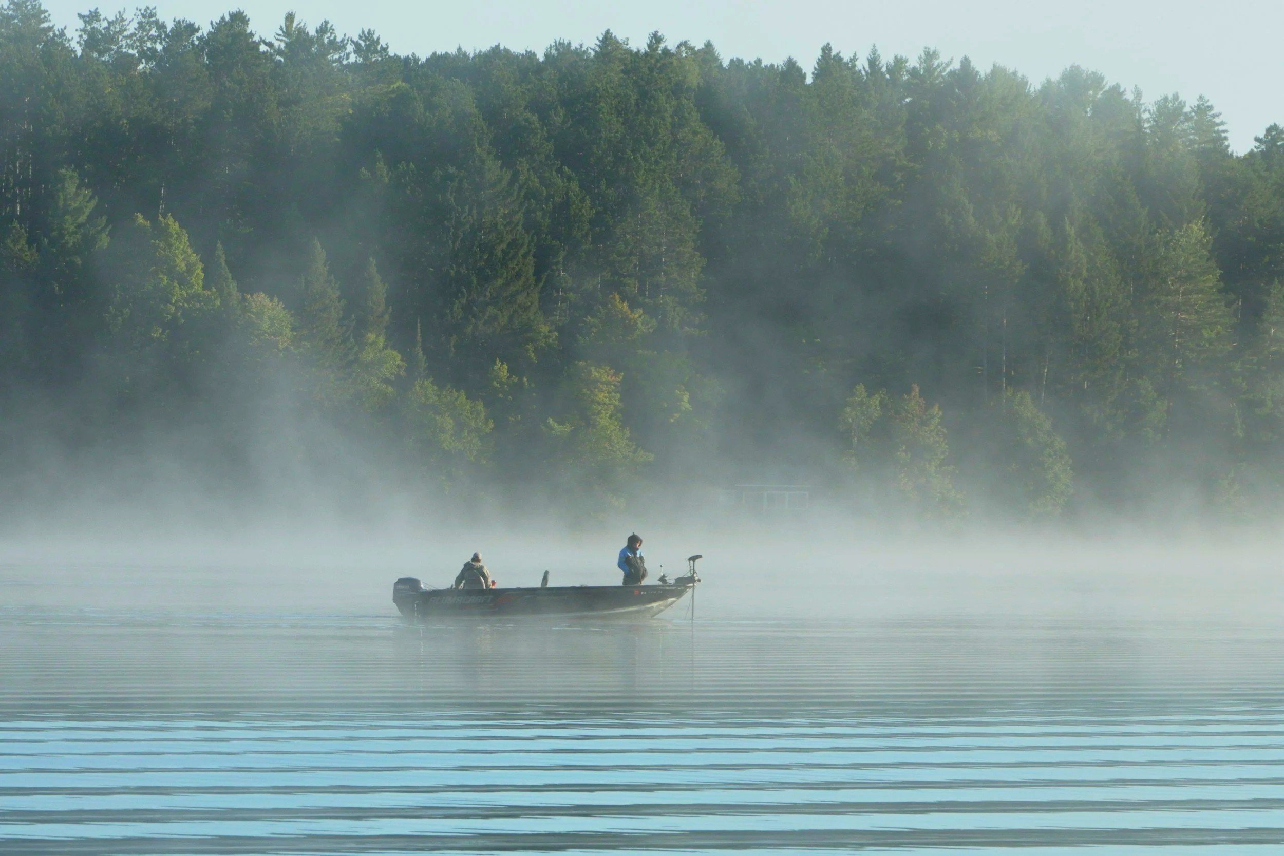 Two people in a small boat on a misty lake