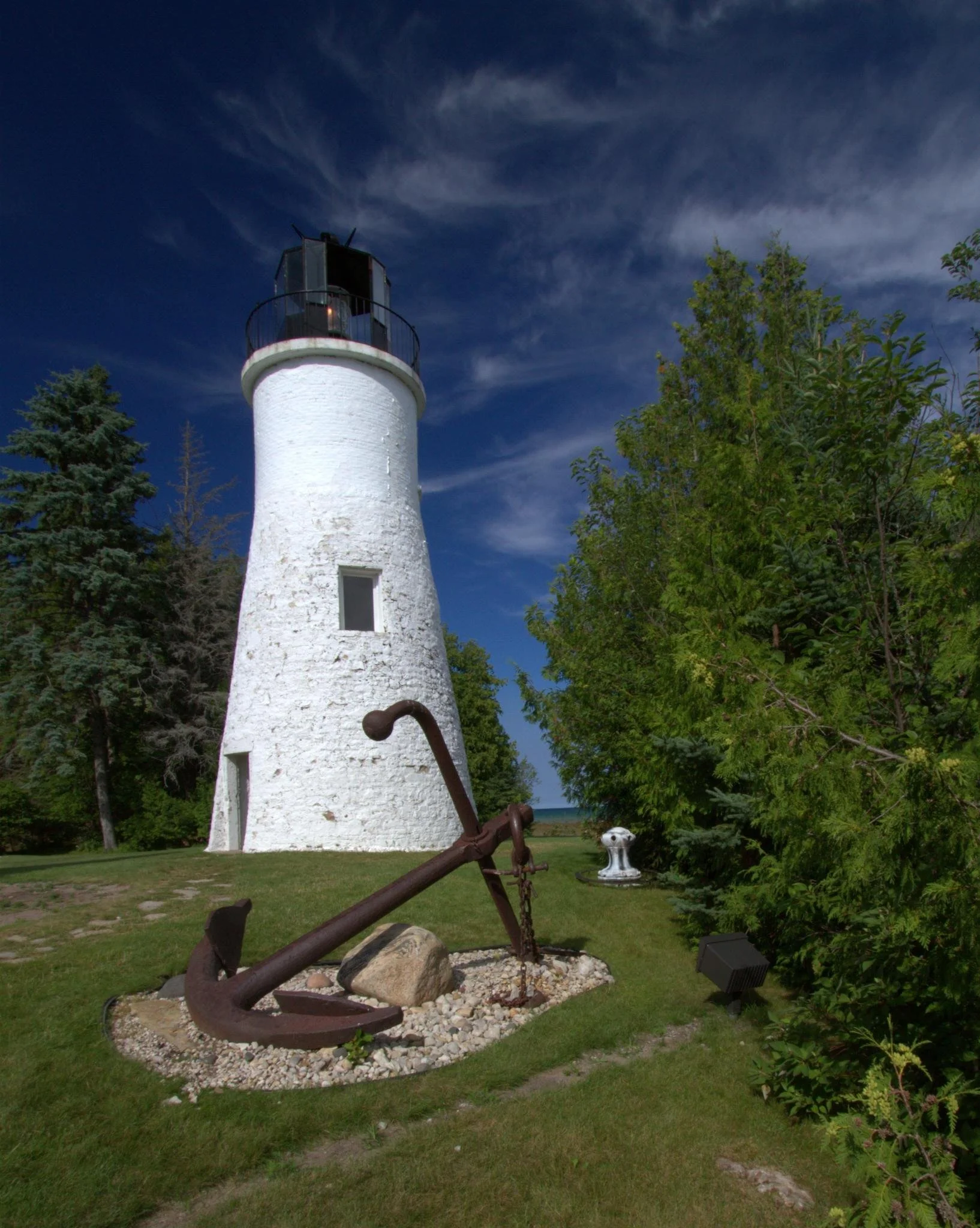 An old ship's anchor resting at the foot of the Old Presque Isle Lighthouse on Lake Huron