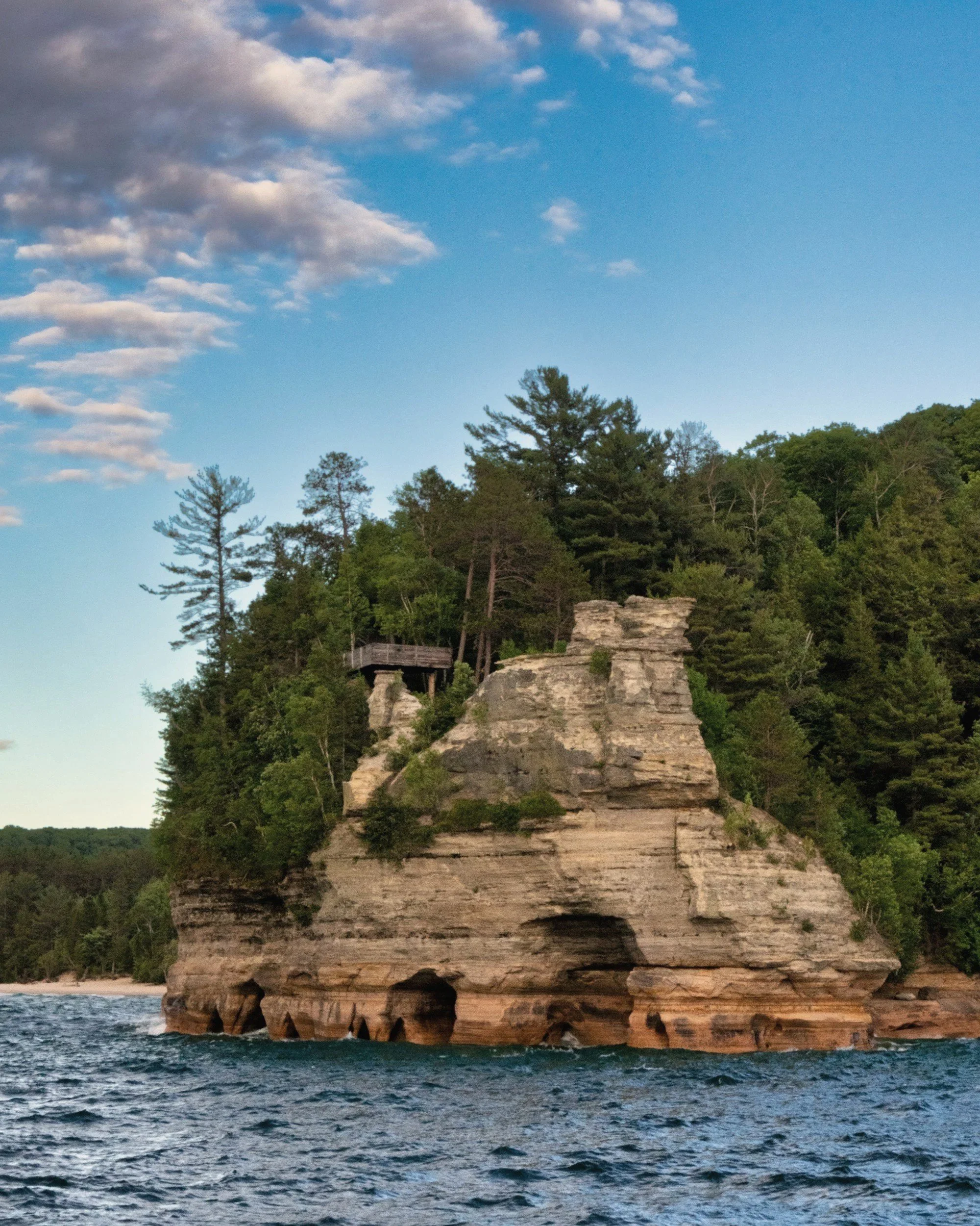 A sandstone bluff topped with pine trees rising from the water