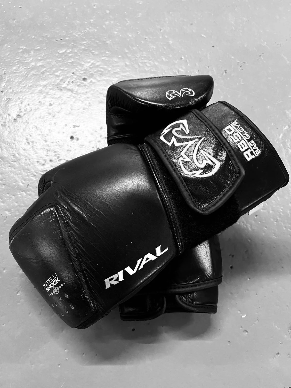 Pair of black Rival boxing gloves on a light-colored textured surface.