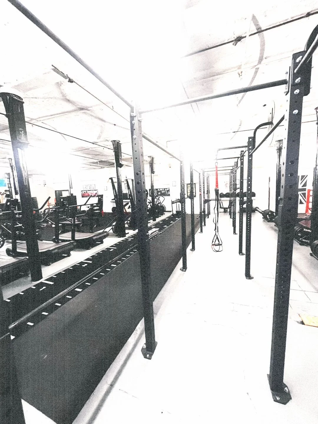 Empty gym with black workout equipment and pull-up bars.