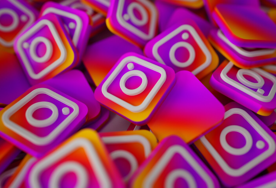 Multiple colorful square blocks with the Instagram logo in white on a vibrant pink, purple, orange, and yellow gradient background.