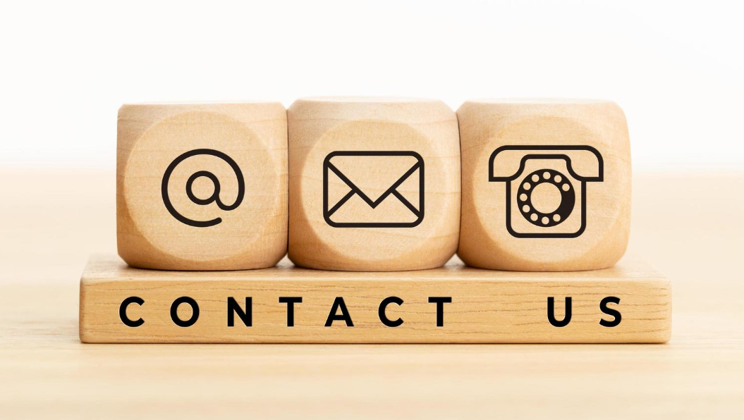 Wooden blocks with icons of a globe, an envelope, and a rotary phone, with the words 'CONTACT US' underneath.