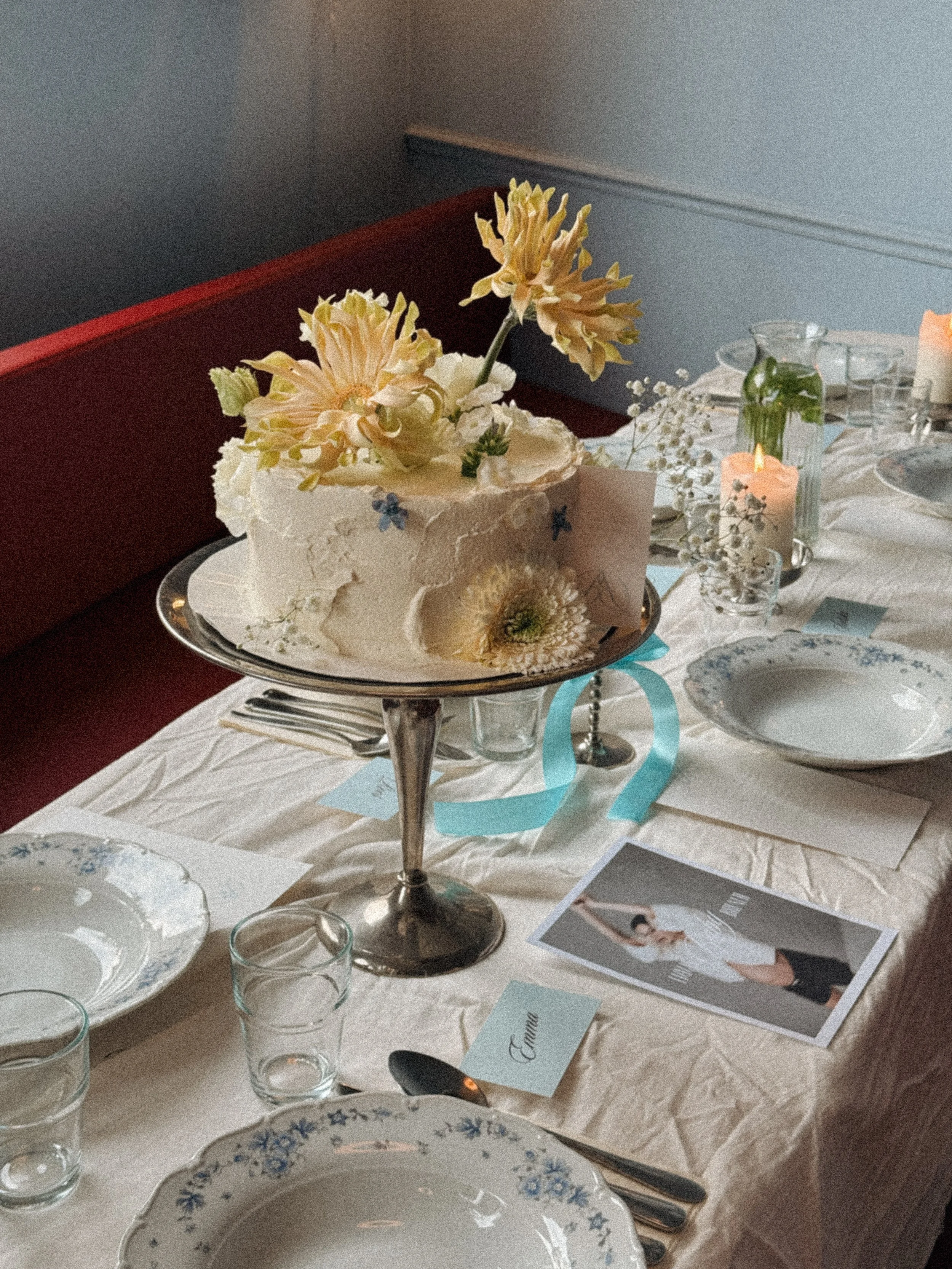 Een feestelijk gedekte tafel met een taart op een zilveren standaard, een bloemstuk, kaarsen en tafeldecoratie voor catering.