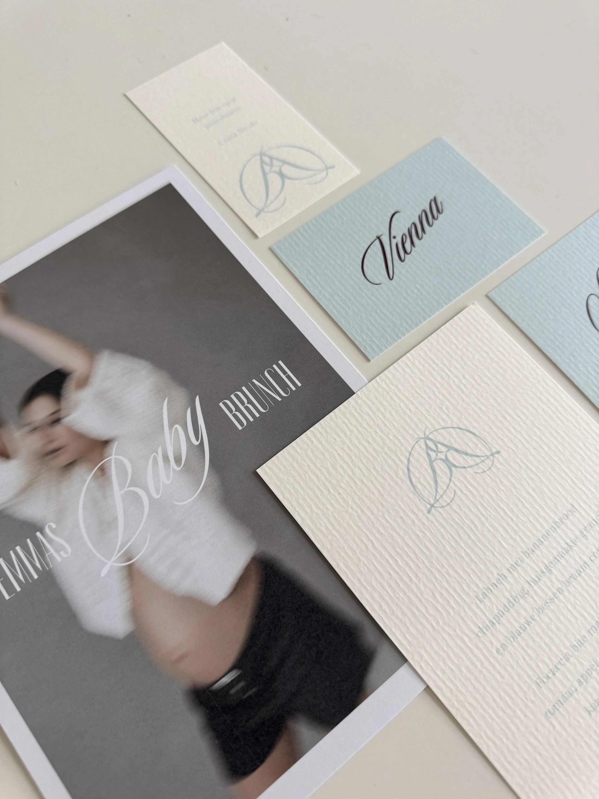Geboorte‑ of uitnodigingskaarten met de naam ‘Vienna’ in zachte pastelkleuren, met een vervaagde foto van een zwangere vrouw.