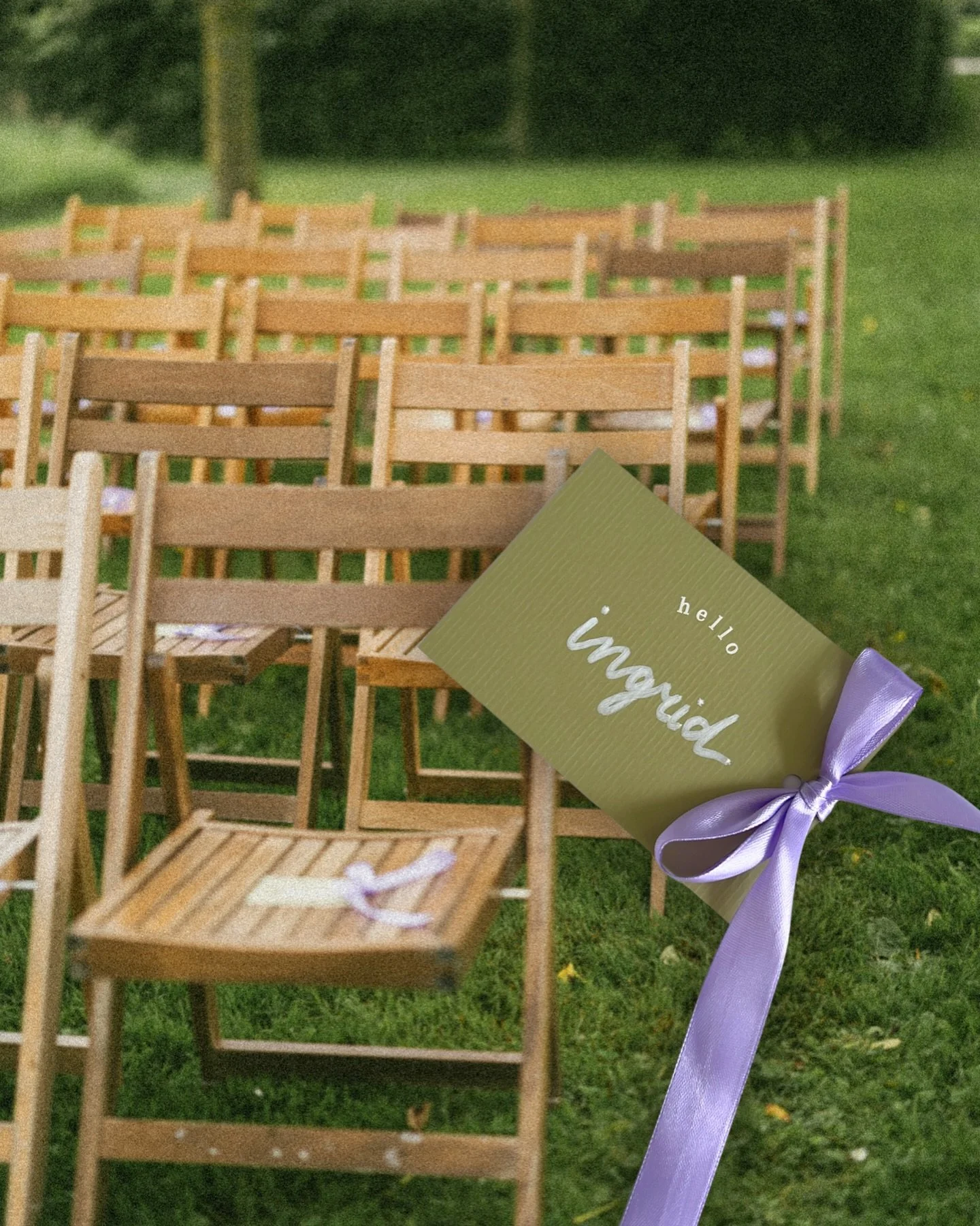 Buitenopstelling voor een bruiloft met houten stoelen en een bordje met de woorden ‘hello’ en ‘bride’, versierd met een paarse strik.