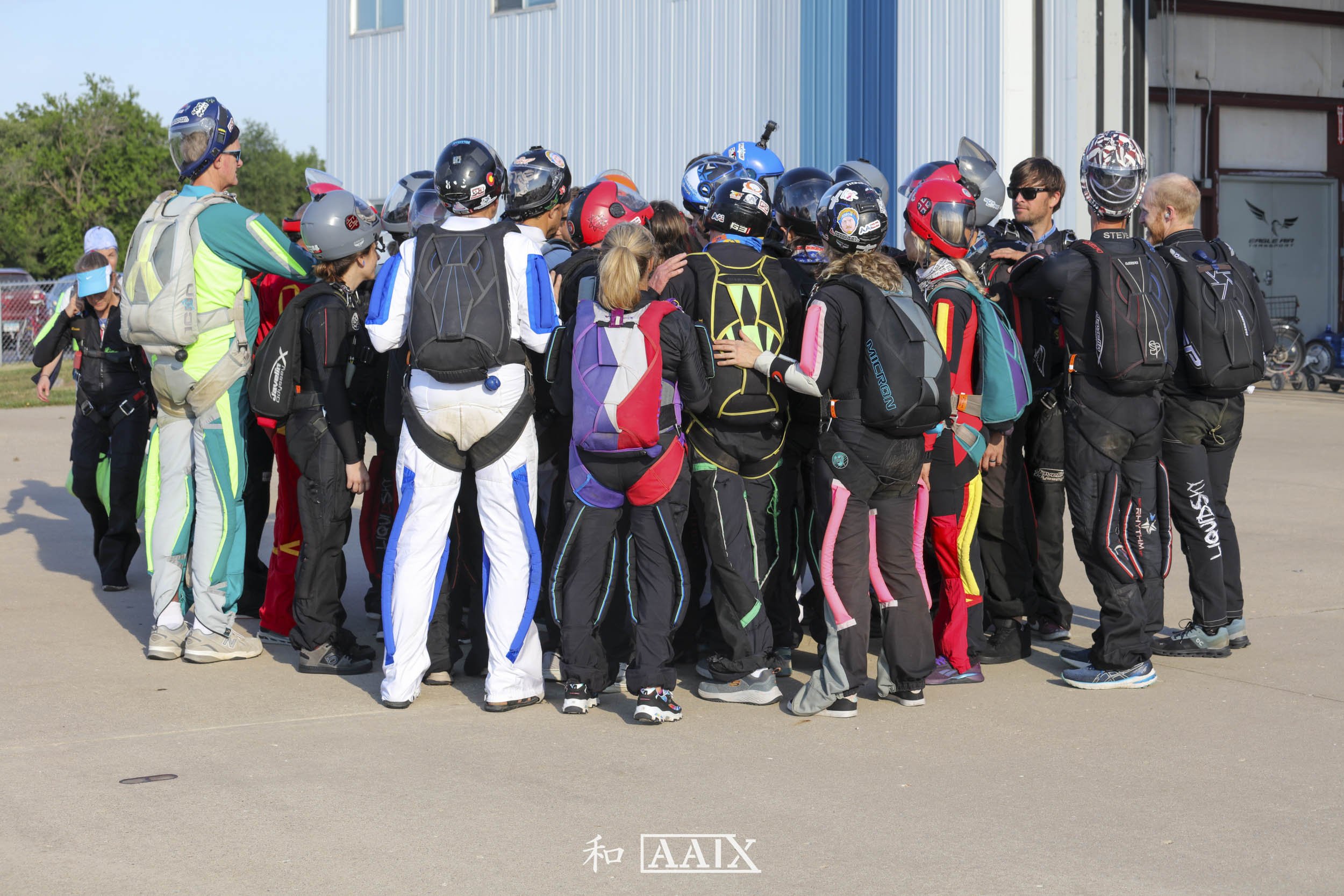 Group of people wearing motorcycle gear gathered outside a building, likely preparing for a ride.