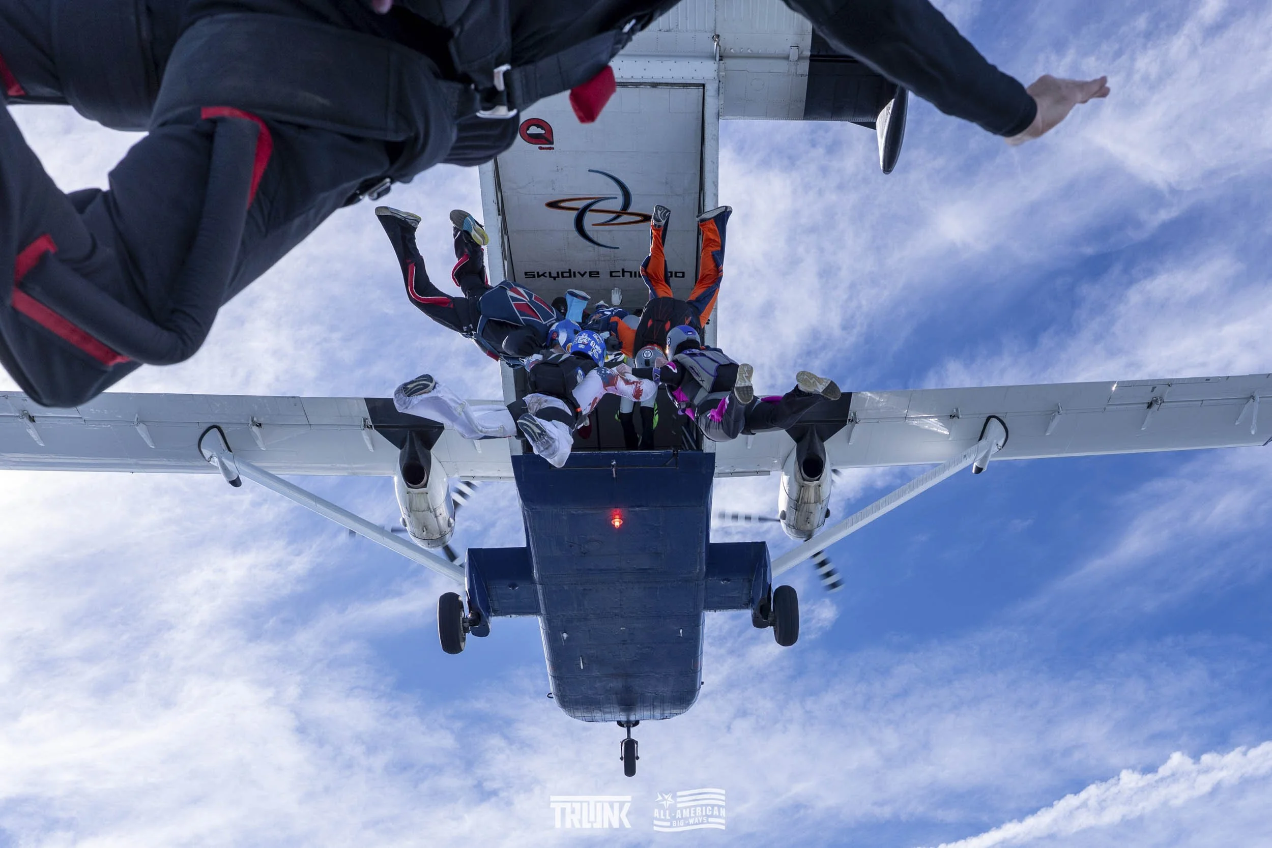 Skydivers jumping from an airplane and exiting the aircraft mid-air.