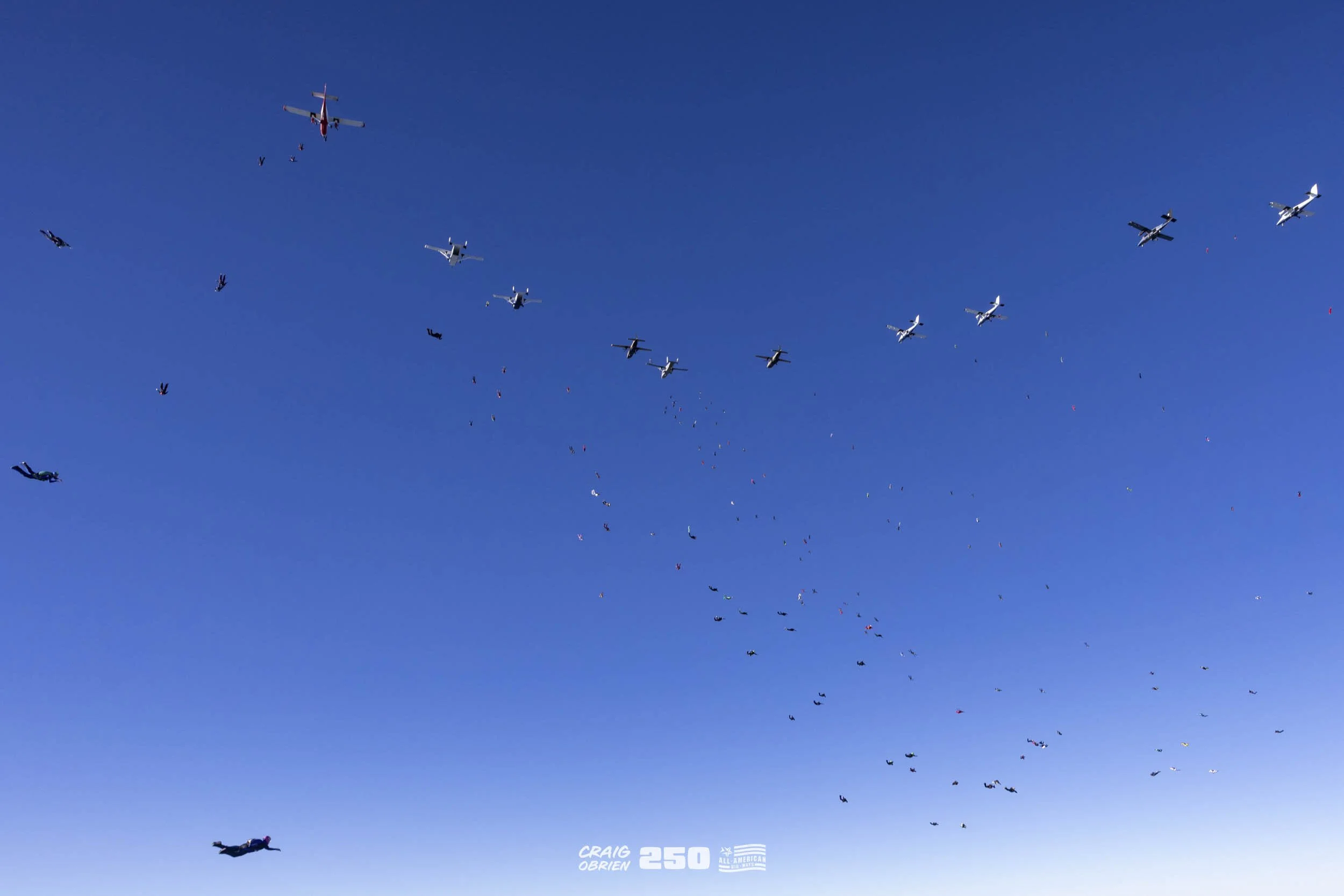 Skydivers descending with parachutes open, colorful parachutes with a blue sky background.