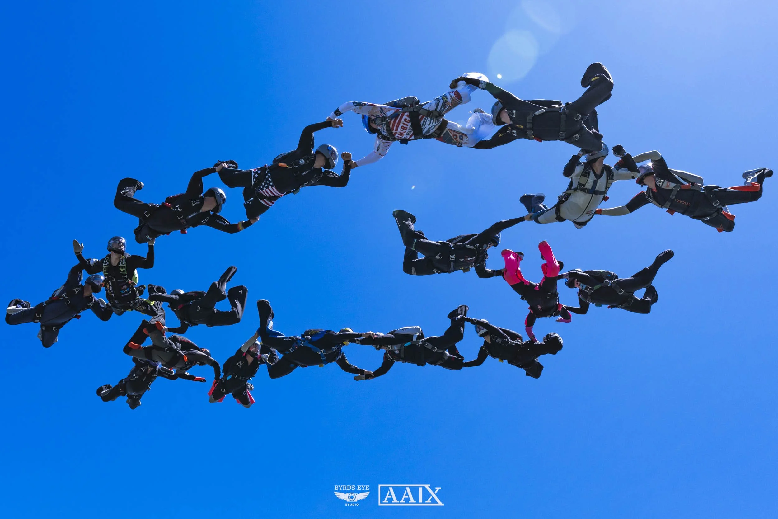 Group of skydivers forming a star shape while freefalling in a clear blue sky.