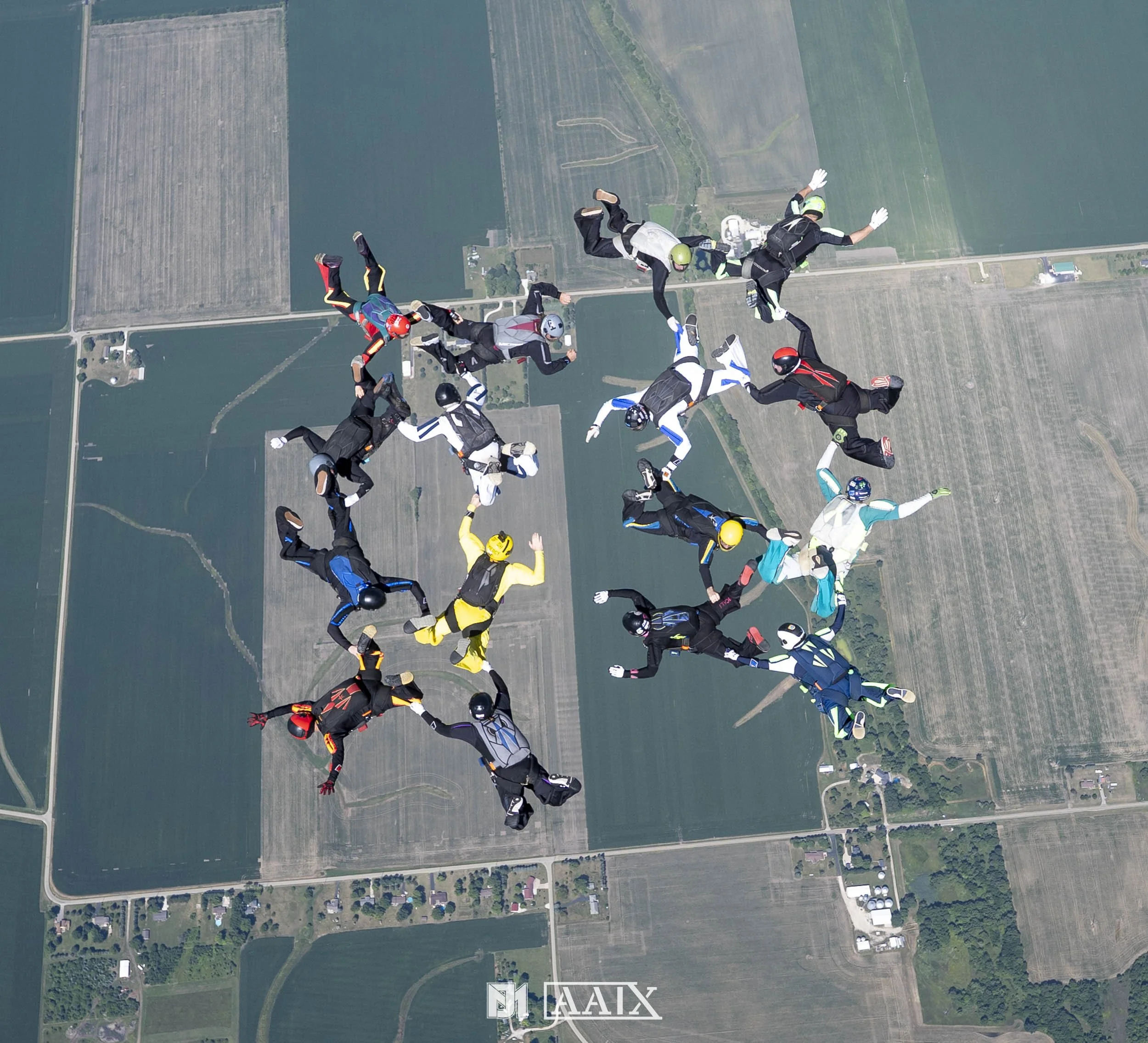 Group of skydivers forming a circle in mid-air over farmland