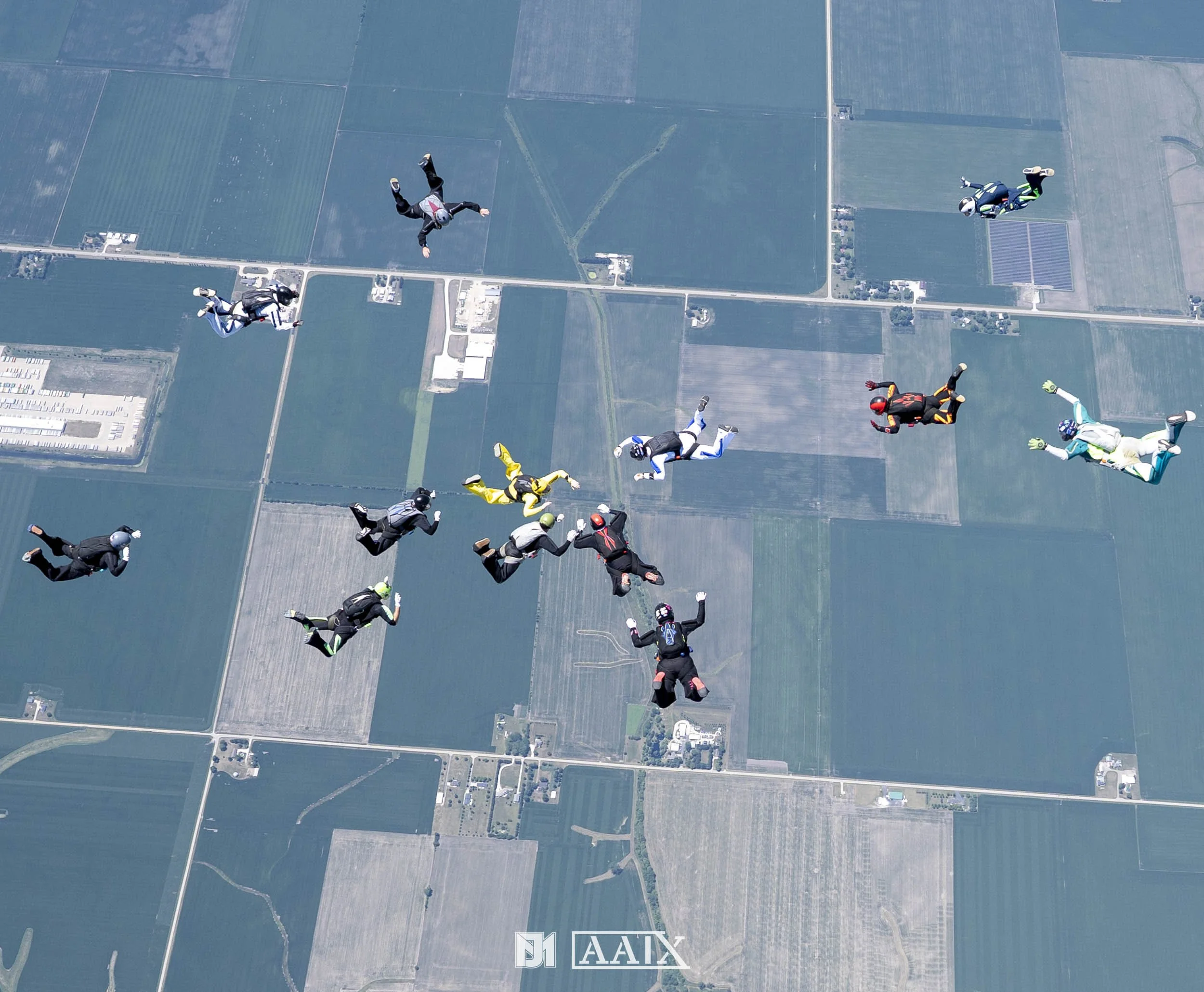 Skydivers in free fall above a patchwork of fields and farmland.