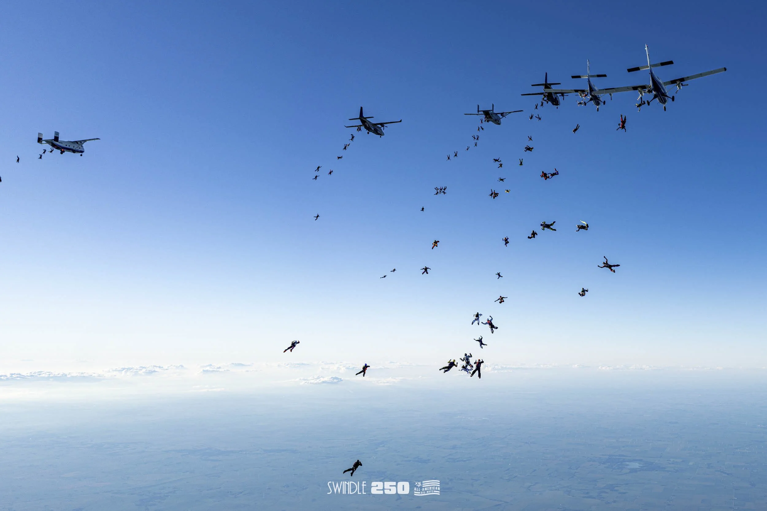 Skydivers free-falling from airplanes in the sky during the Swindle 250 event.