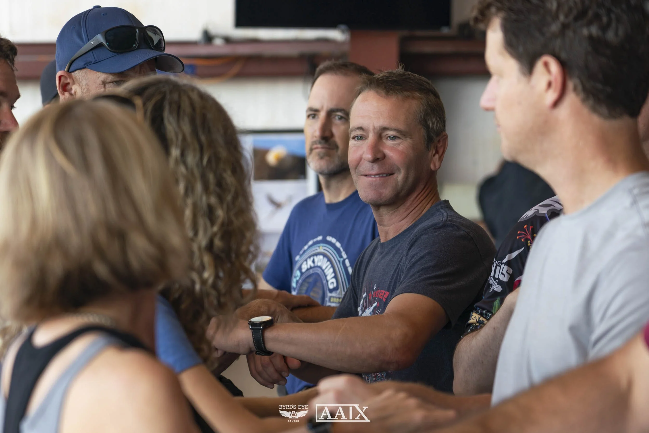 Group of people shaking hands and smiling, indoors.