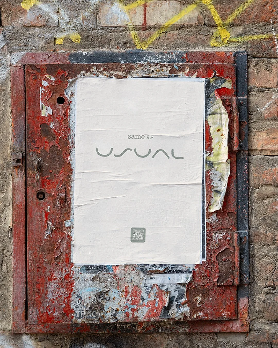 Poster displaying “same as usual” and The Usual logo mounted on a weathered brick wall with layered street textures.