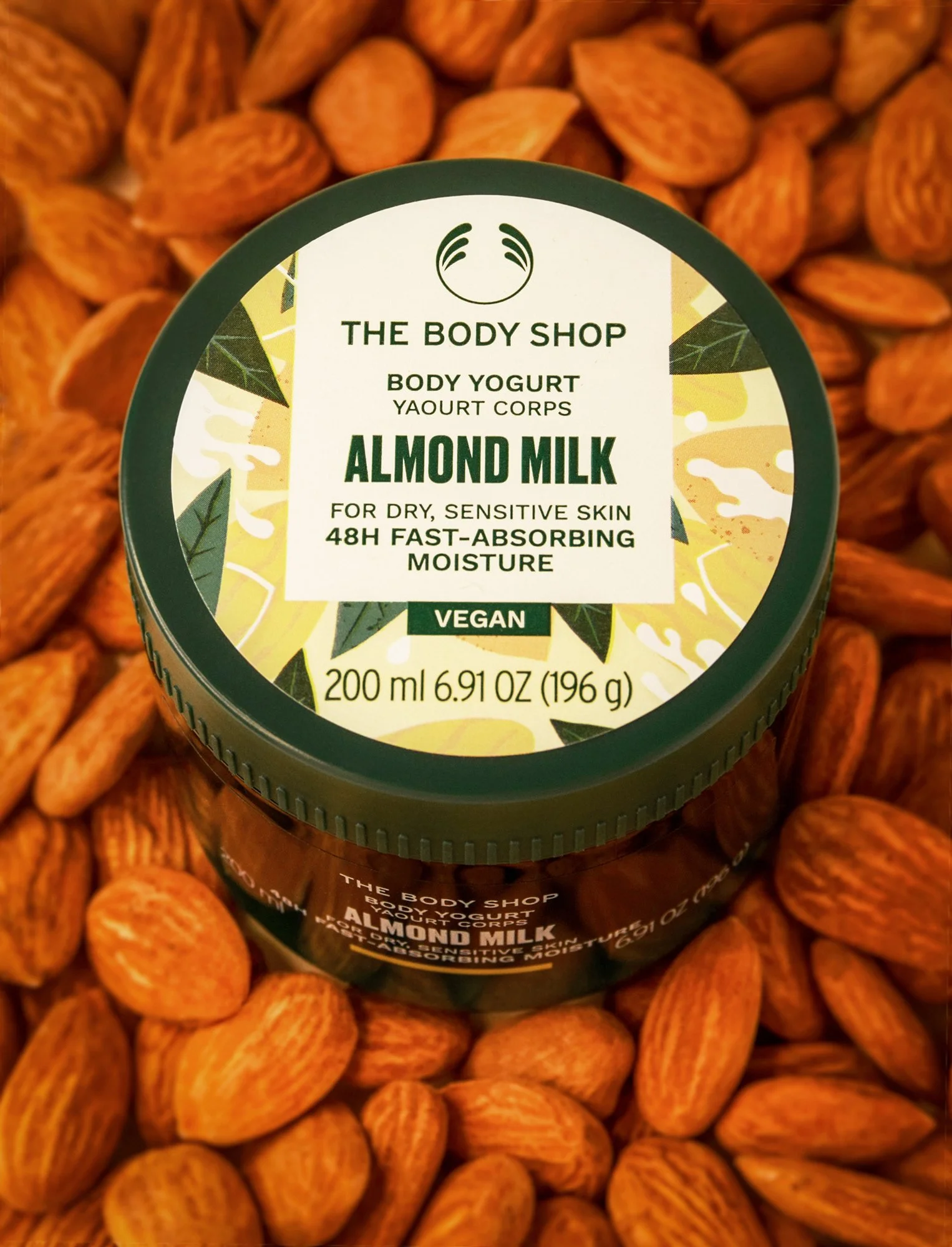 Container of almond milk surrounded by almonds.