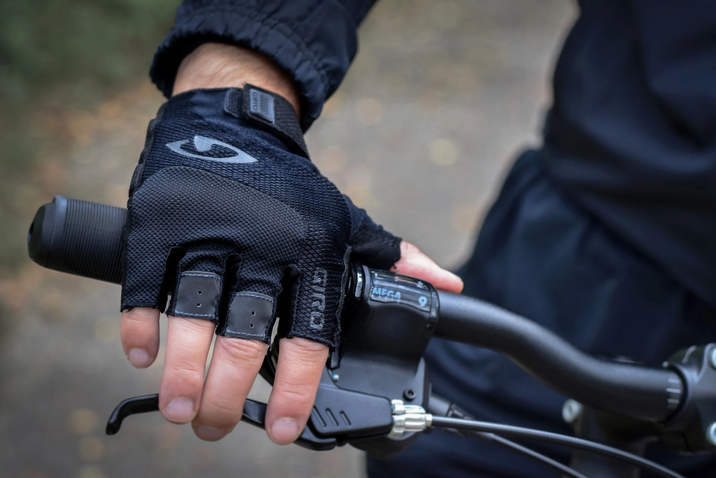 Close-up of a person's gloved hand holding the throttle of a bicycle handlebars. 