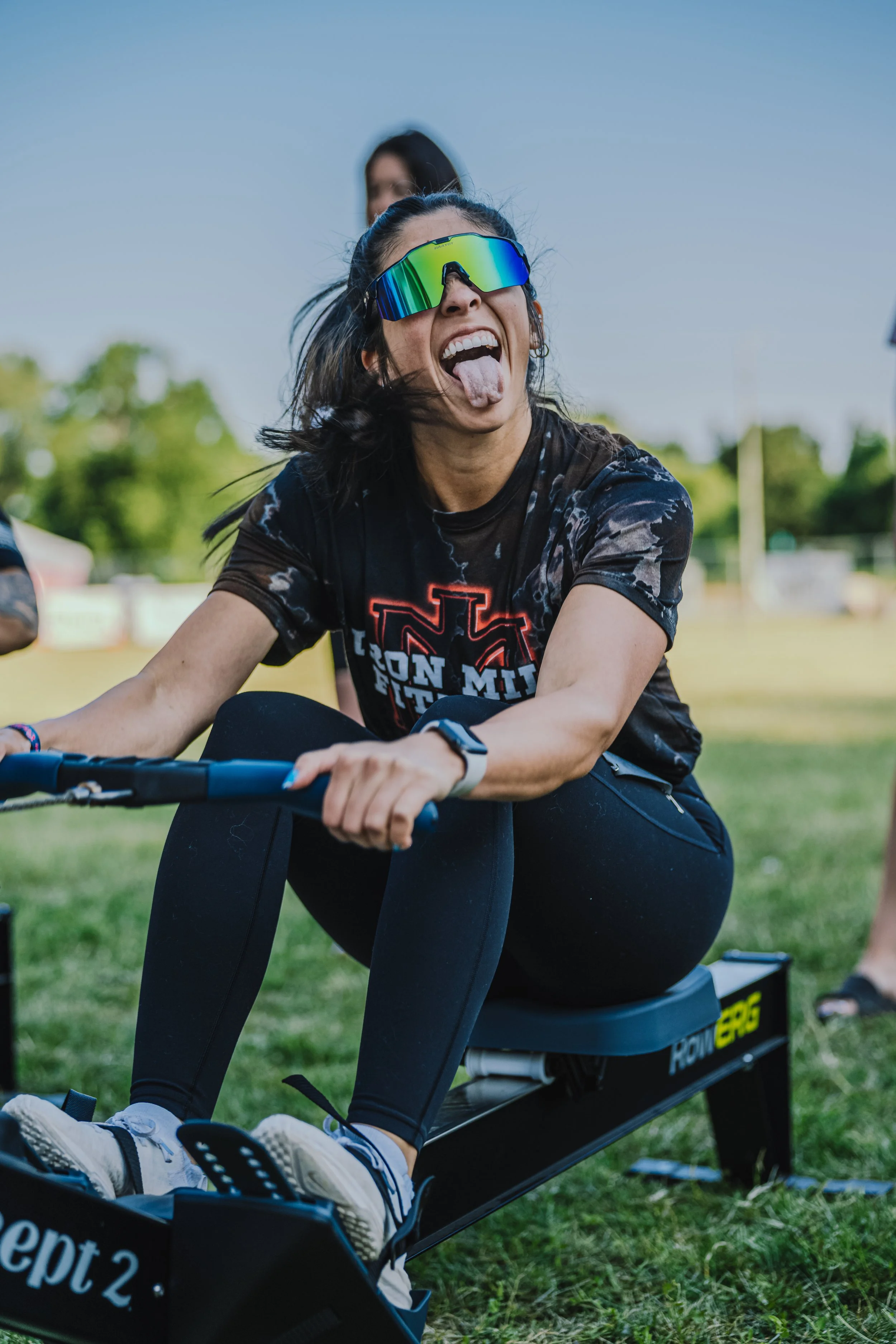 Woman making a silly face while participating in a rowing activity outdoors.