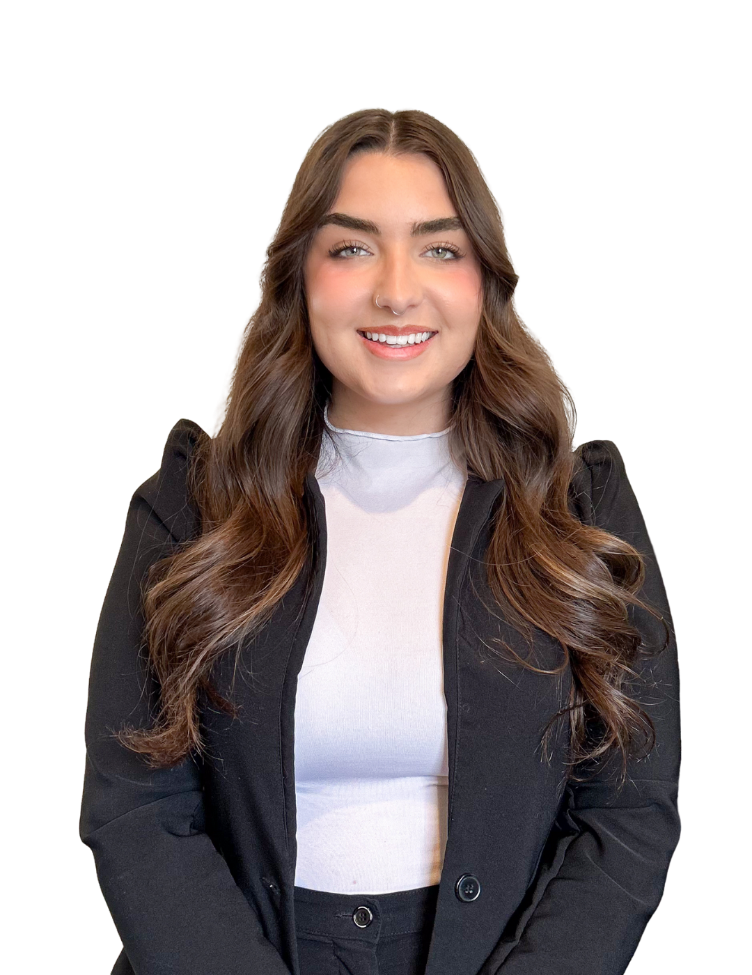 A young woman with long wavy brown hair, light skin, and a septum piercing, smiling, wearing a white top and black blazer.