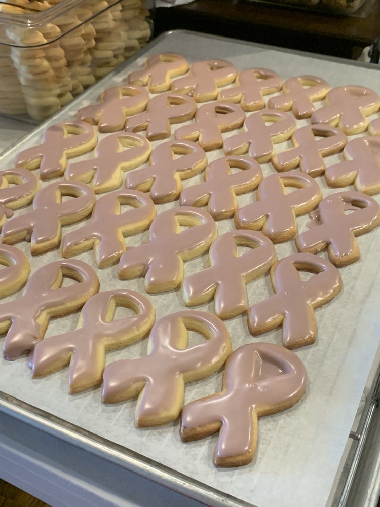 Cookies in the shape of pink awareness ribbons on a baking sheet.