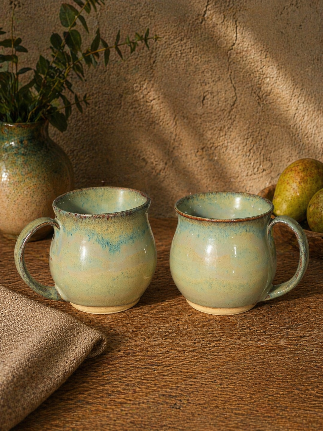 Two ceramic mugs with flowing green glaze