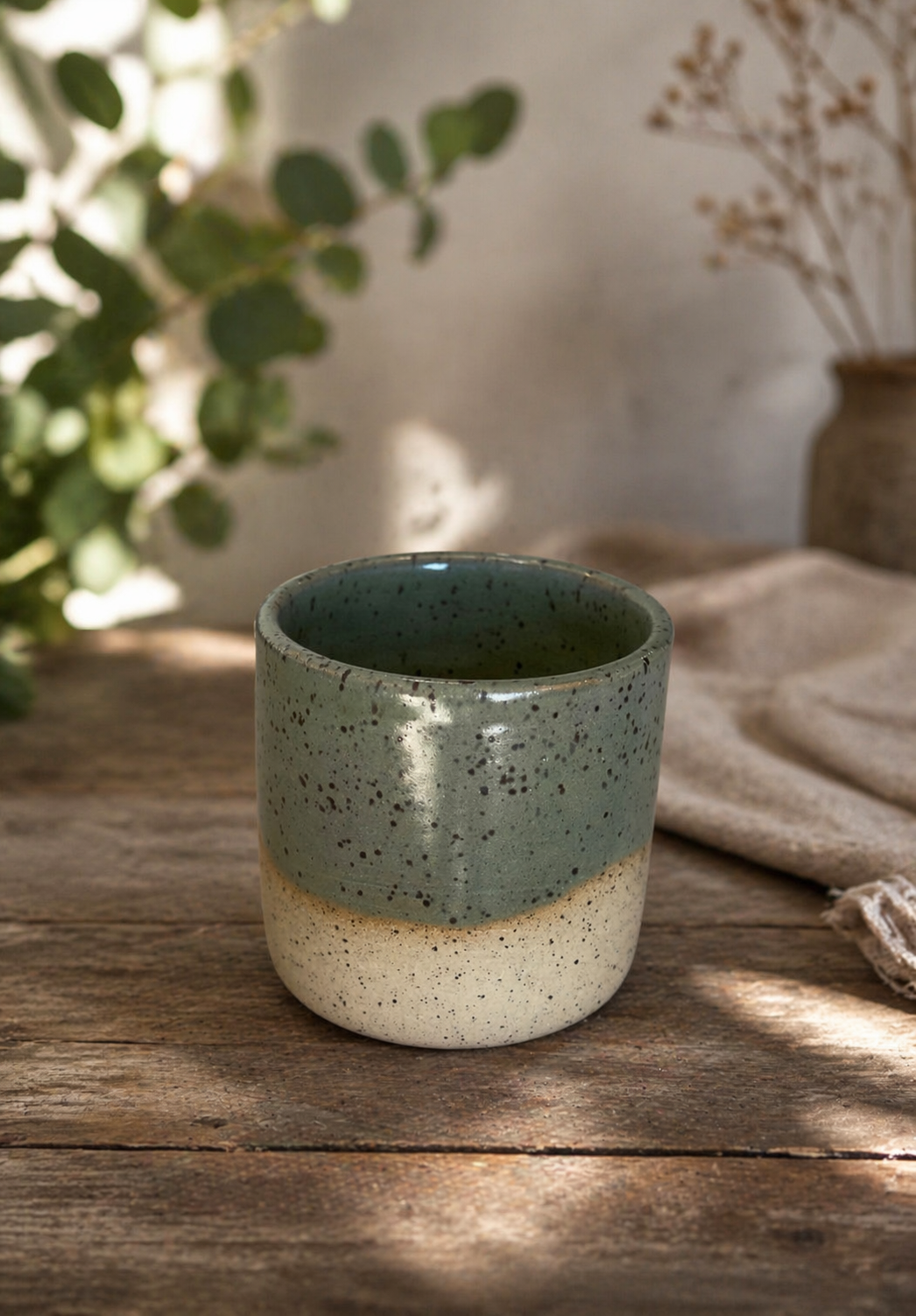 A ceramic espresso cup with a green top half and a cream bottom half, 
