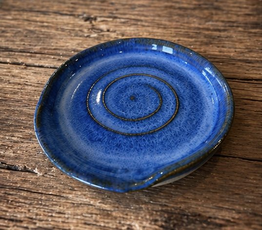 A small, round, blue ceramic spoon rest