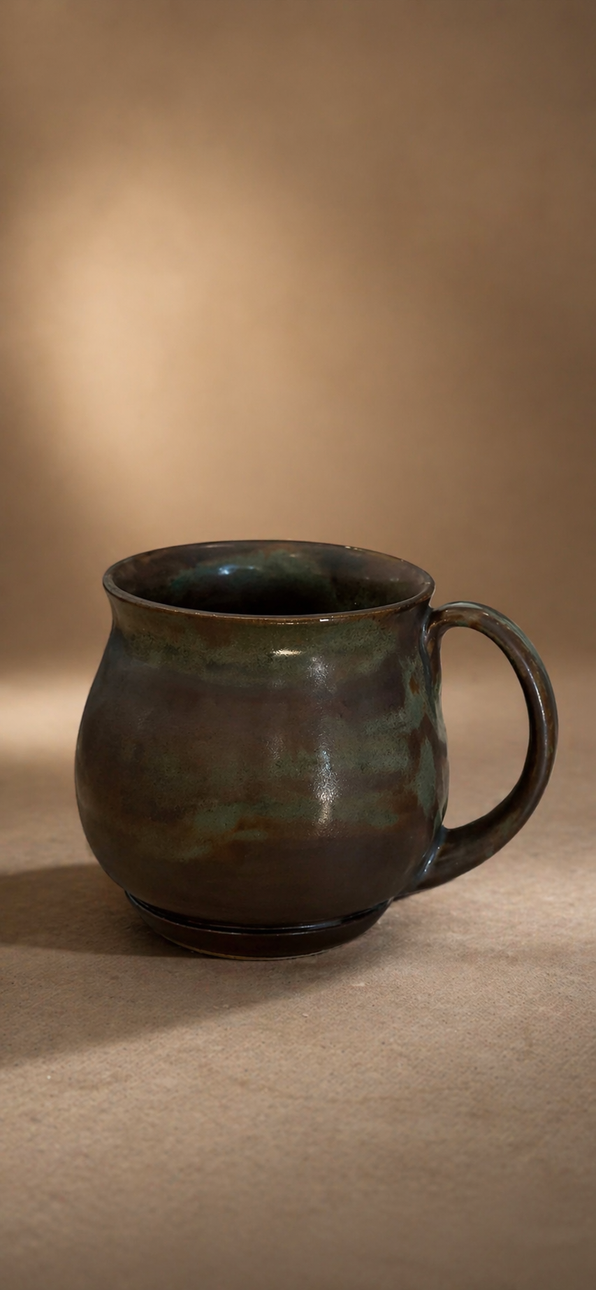 A ceramic mug with a rounded body dark brown/green tones