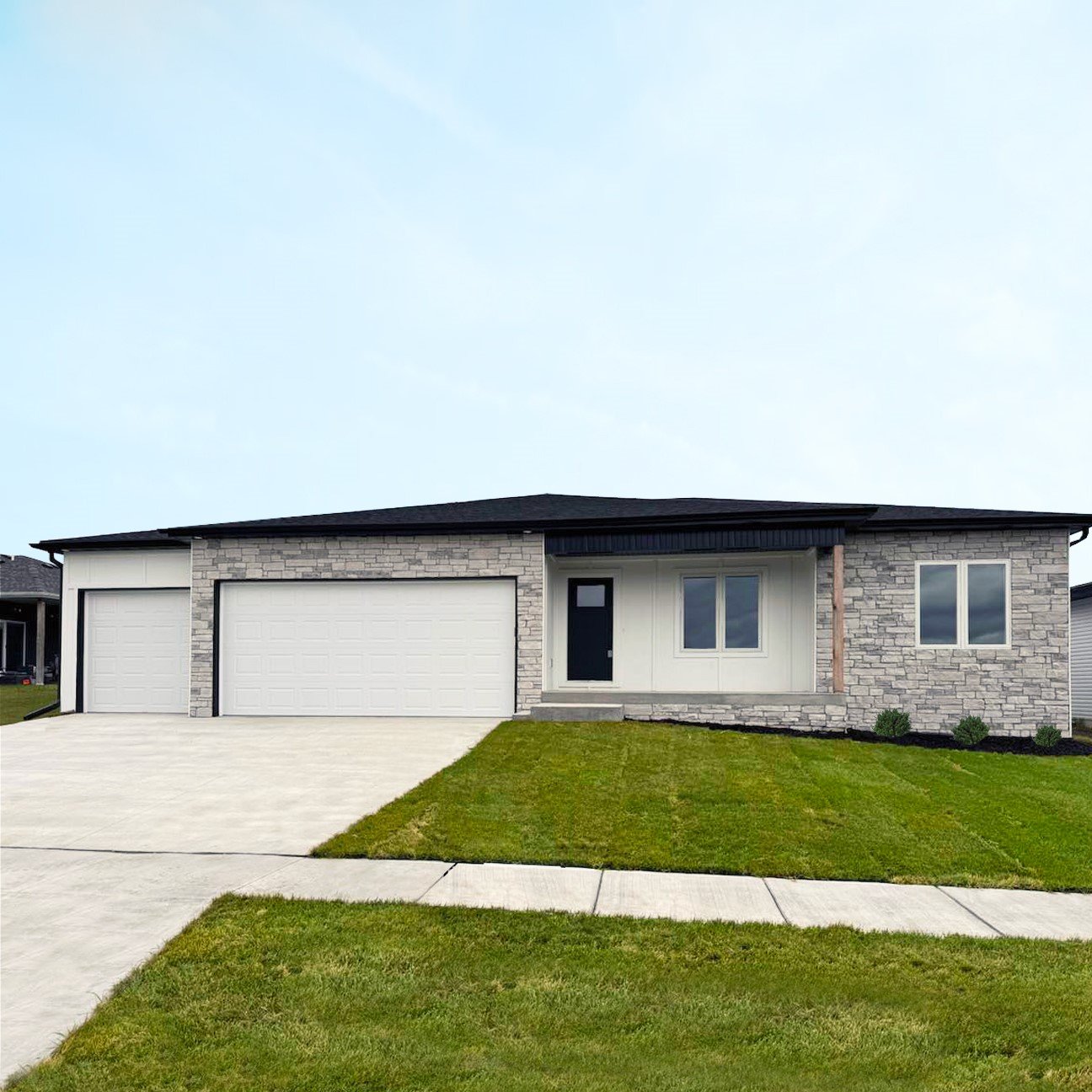 Front view of a modern single-story house with a brick and siding exterior, two-car garage, and a well-maintained lawn.