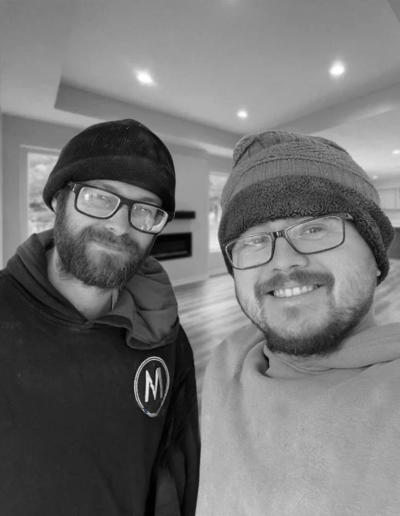 A photo of McKeil Michalek and Joshua Sisco in the living room of one of their newly constructed homes.