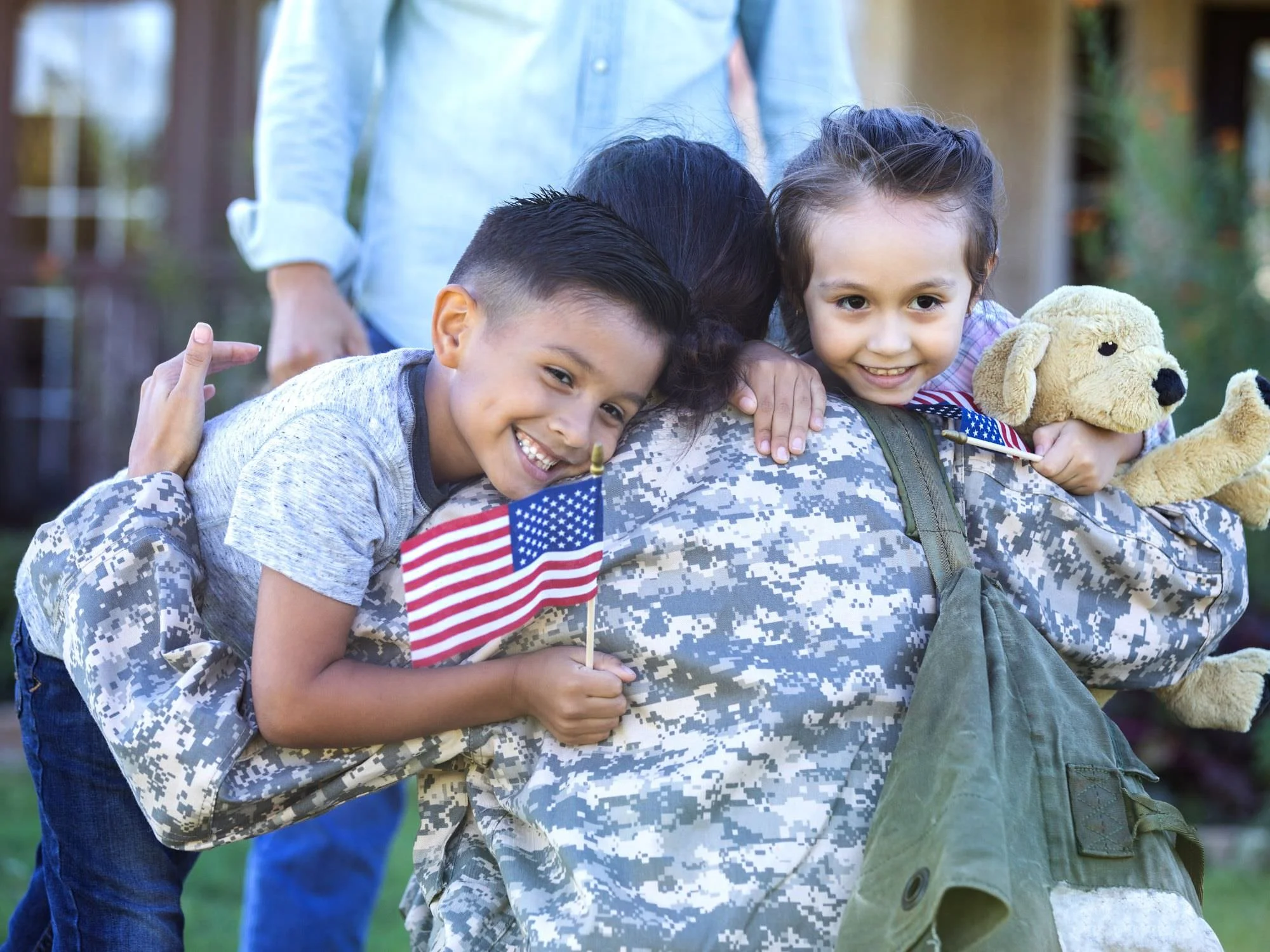 Daughter and son hugging mom who's in fatigues.