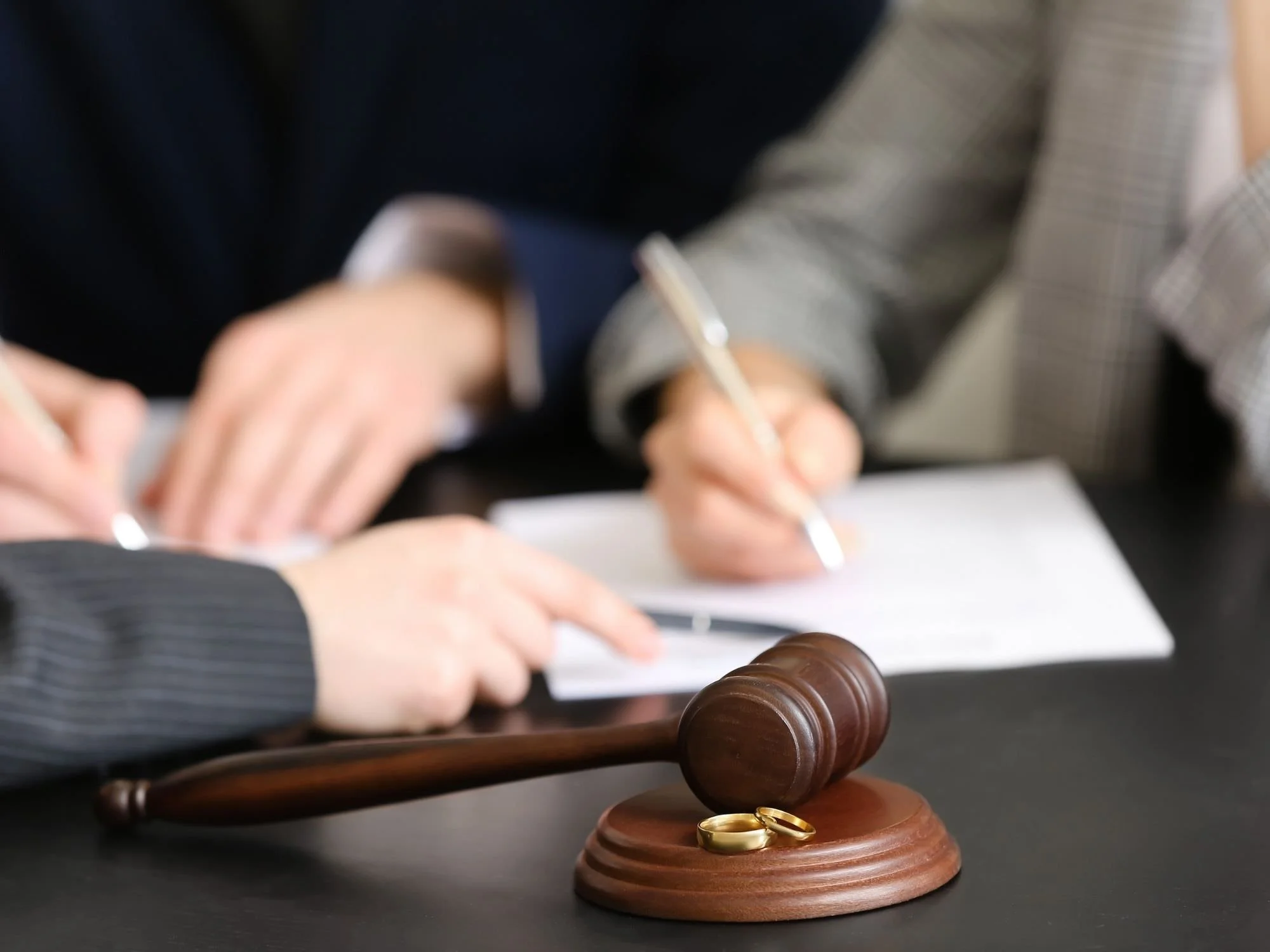 people signing divorce papers, rings taken off