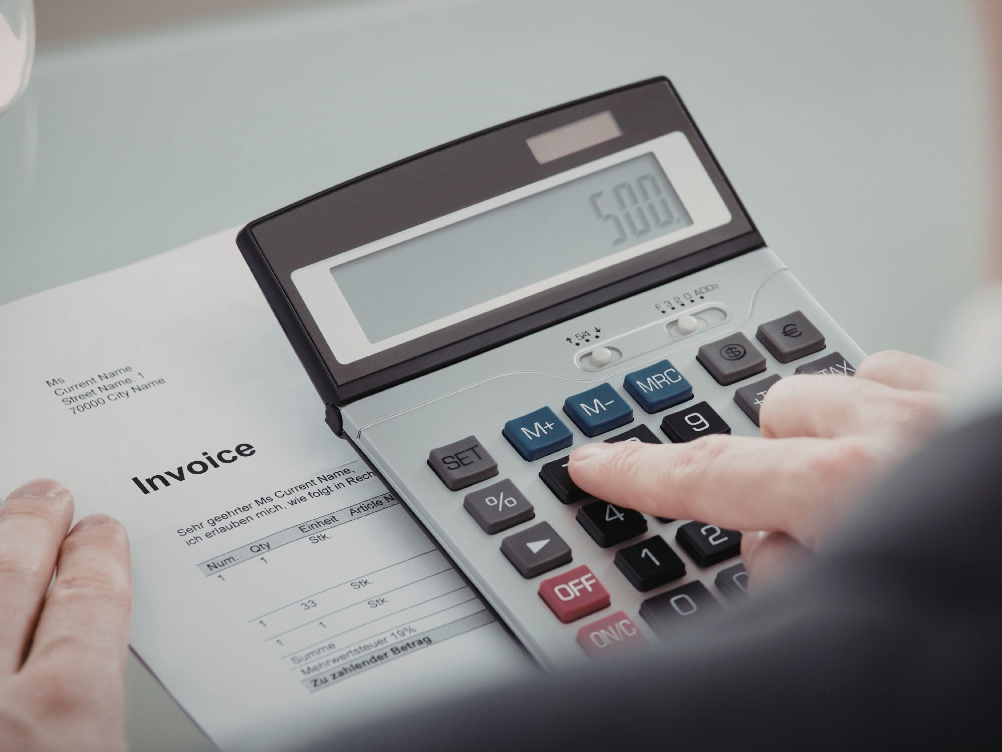 someone looking at an invoice and crunching numbers on a calculator - QRDO divorce