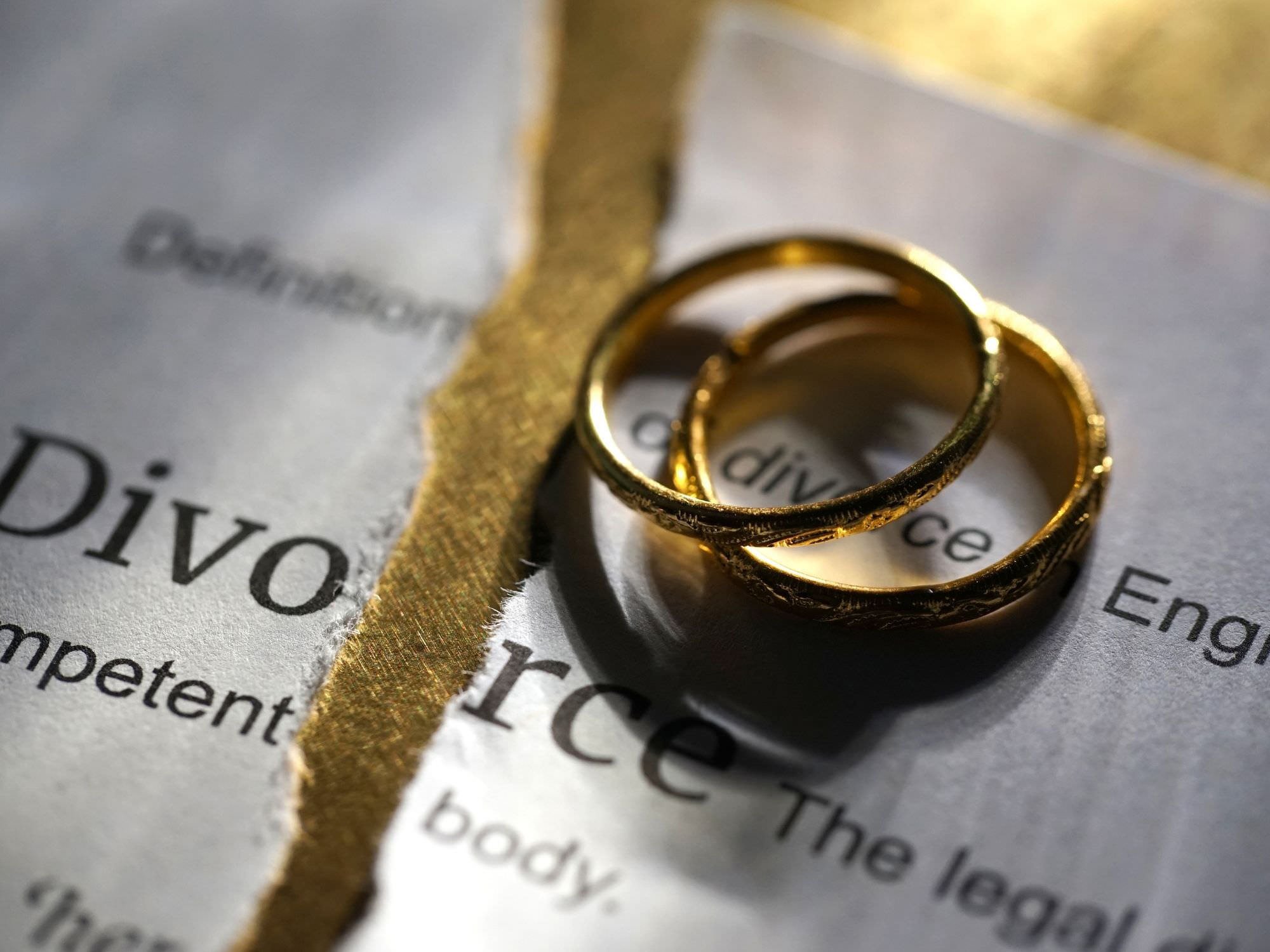 divorce paperwork torn in half with rings on top - Dividing Assets in Divorce