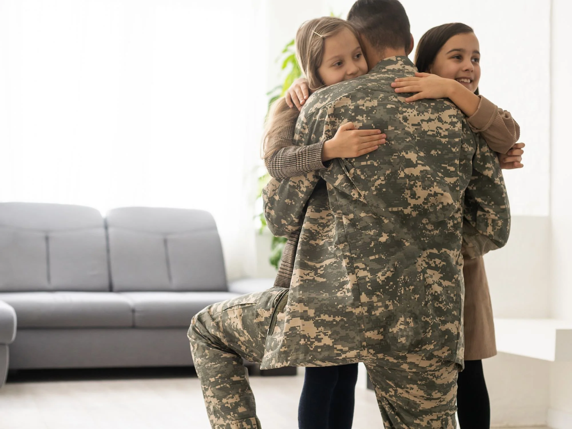 Daughters hugging their dad who's in the military - Military Pension Divorce