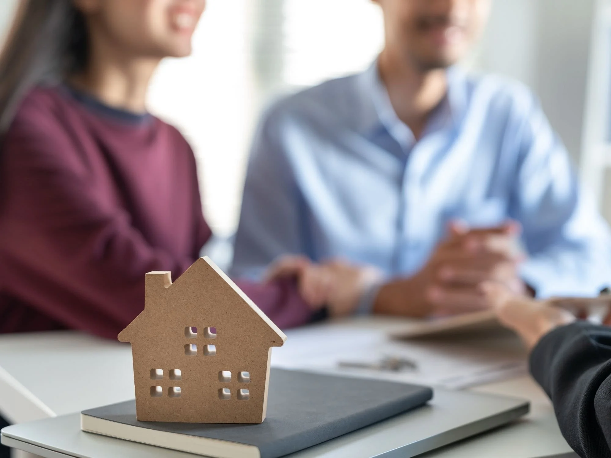 A couple reviewing documents with a wooden house - Inheritance and Estate Planning