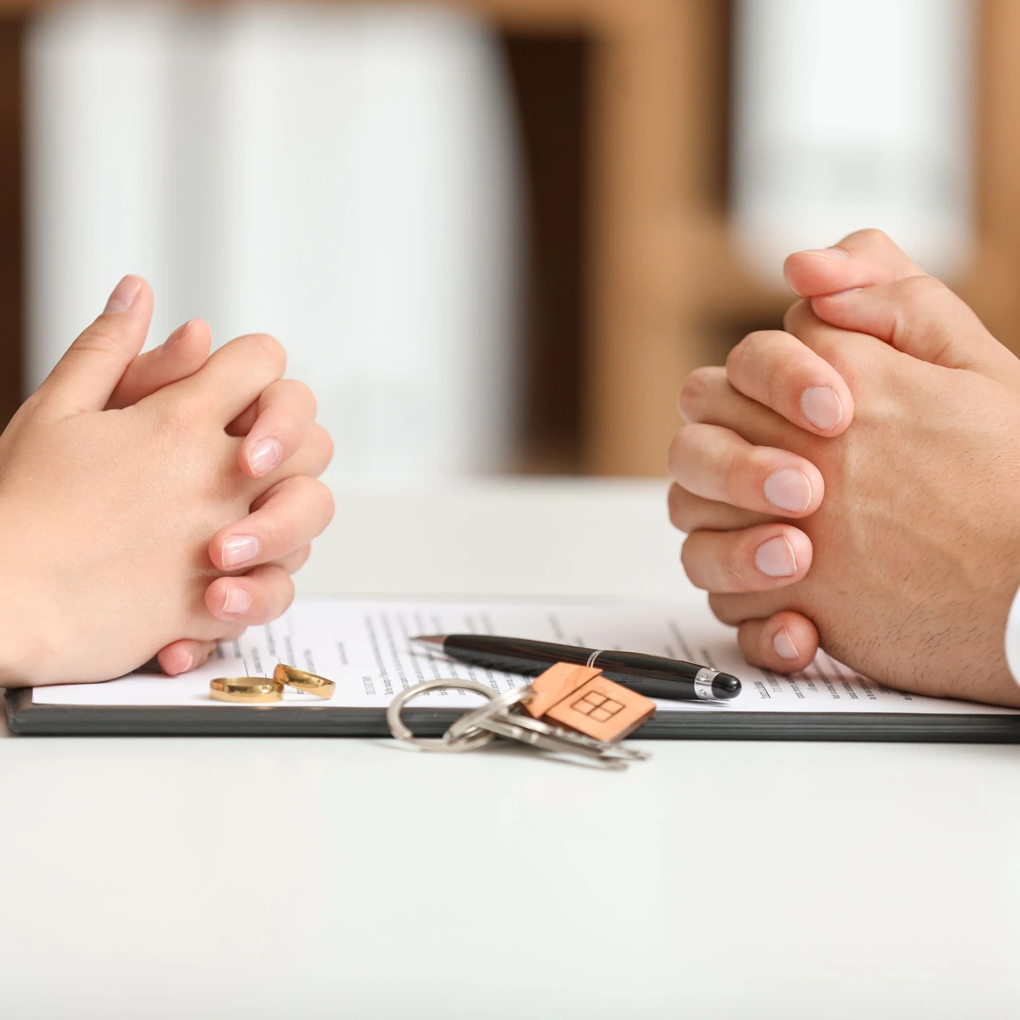 Two people's folded hands across from each other - Divorce Financial Planning